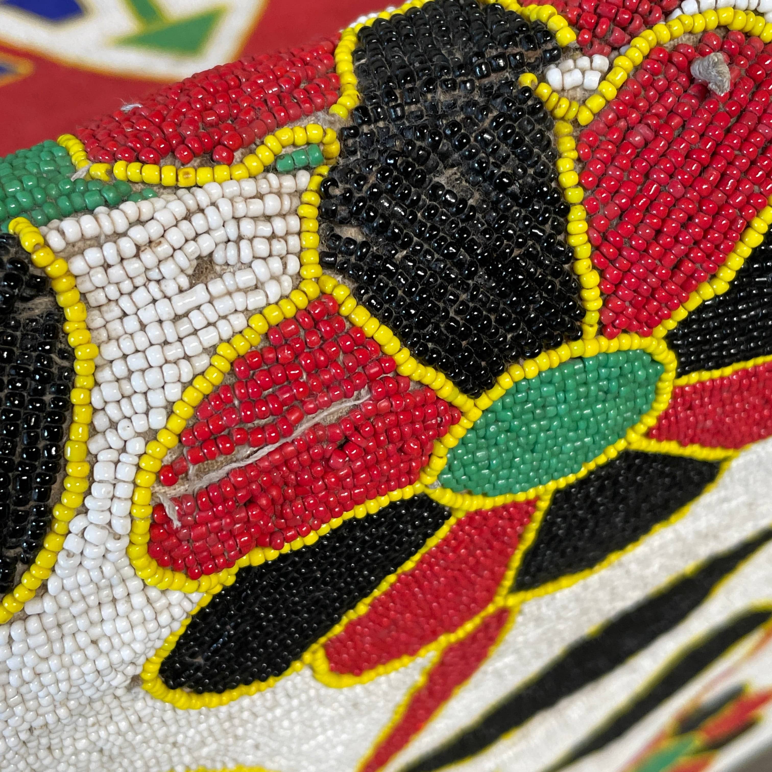 The Handmade Hand Beaded African Yoruba Chair (on hold) features a high backrest, wooden legs, and vibrant upholstery with multicolored geometric and floral patterns inspired by West African artistry.