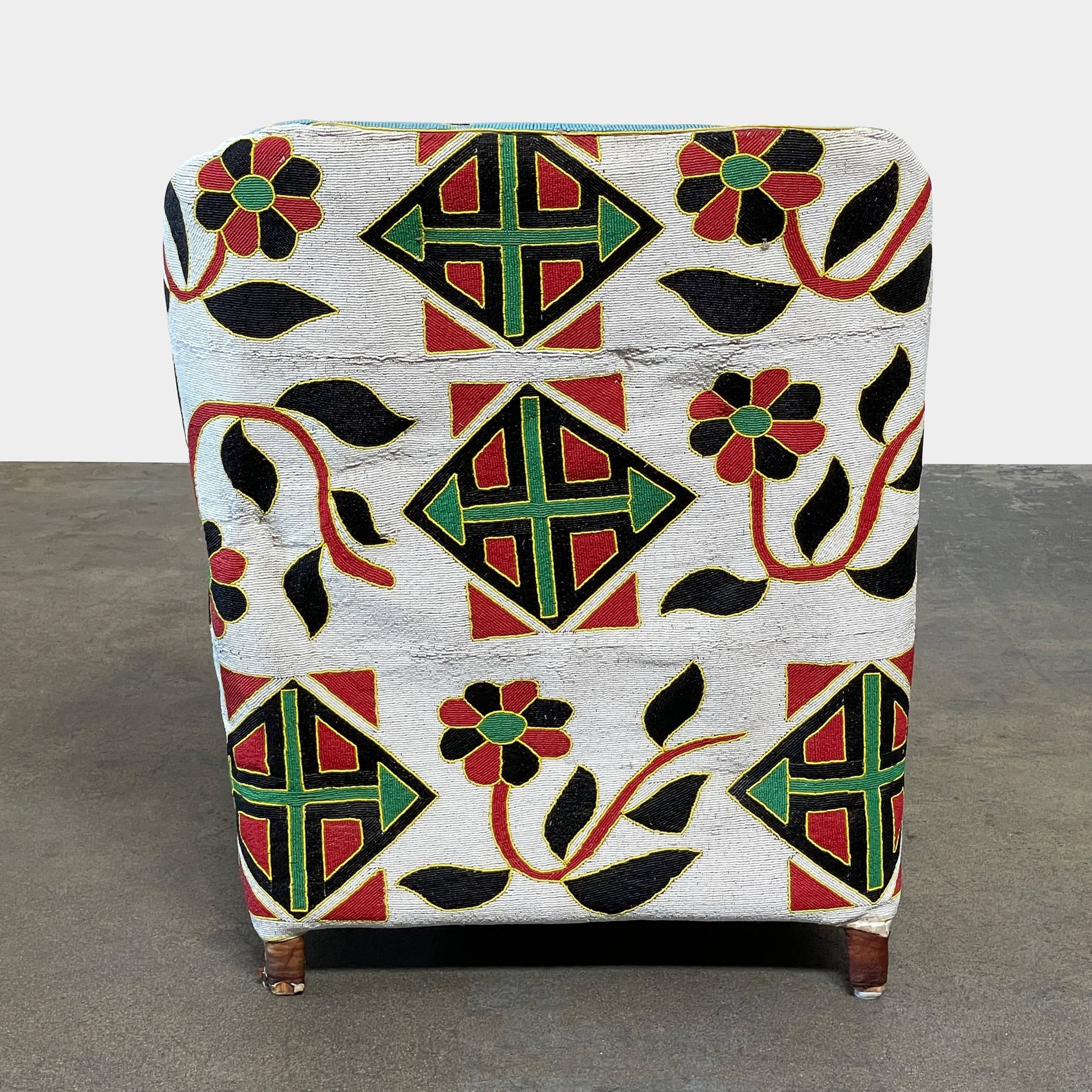The Handmade Hand Beaded African Yoruba Chair (on hold) features a high backrest, wooden legs, and vibrant upholstery with multicolored geometric and floral patterns inspired by West African artistry.