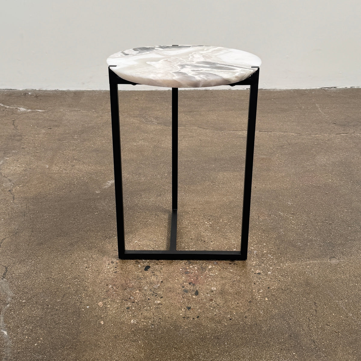 The Baxter Icaro Polar White Marble Accent Table - Small by Baxter showcases a sleek black metal base and a smooth Polar White marble top, photographed against a plain white background.
