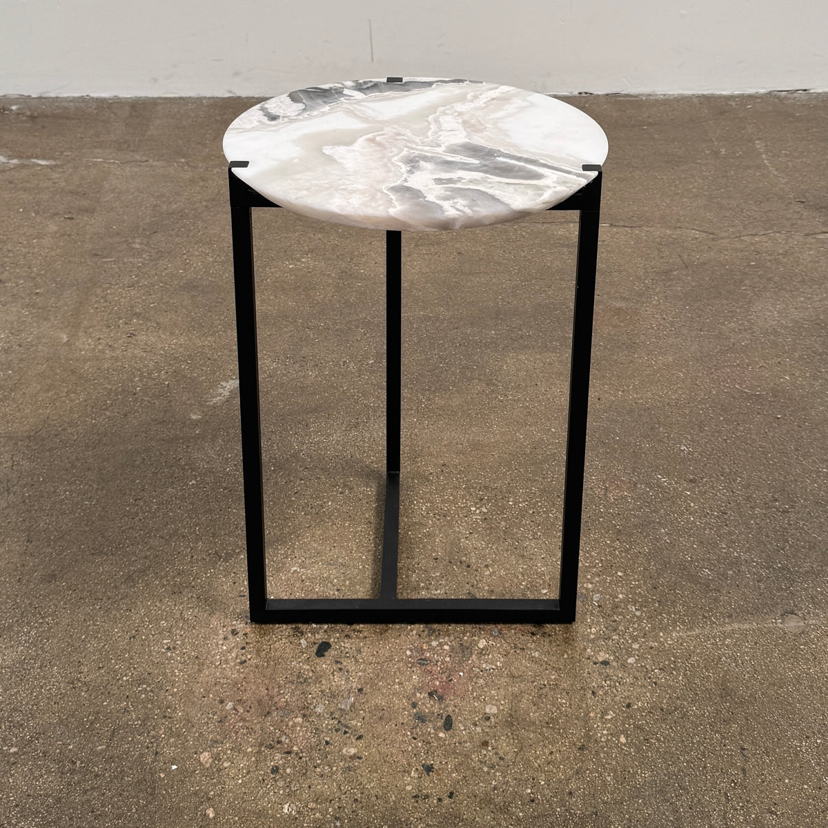 The Baxter Icaro Polar White Marble Accent Table - Small by Baxter showcases a sleek black metal base and a smooth Polar White marble top, photographed against a plain white background.