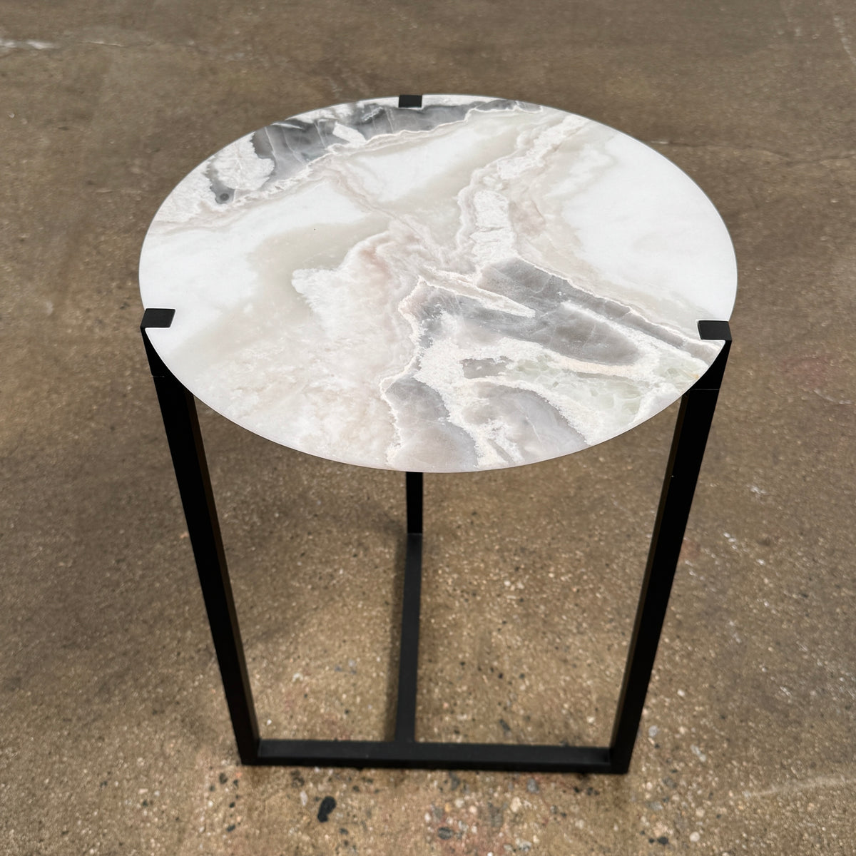 The Baxter Icaro Polar White Marble Accent Table - Small by Baxter showcases a sleek black metal base and a smooth Polar White marble top, photographed against a plain white background.