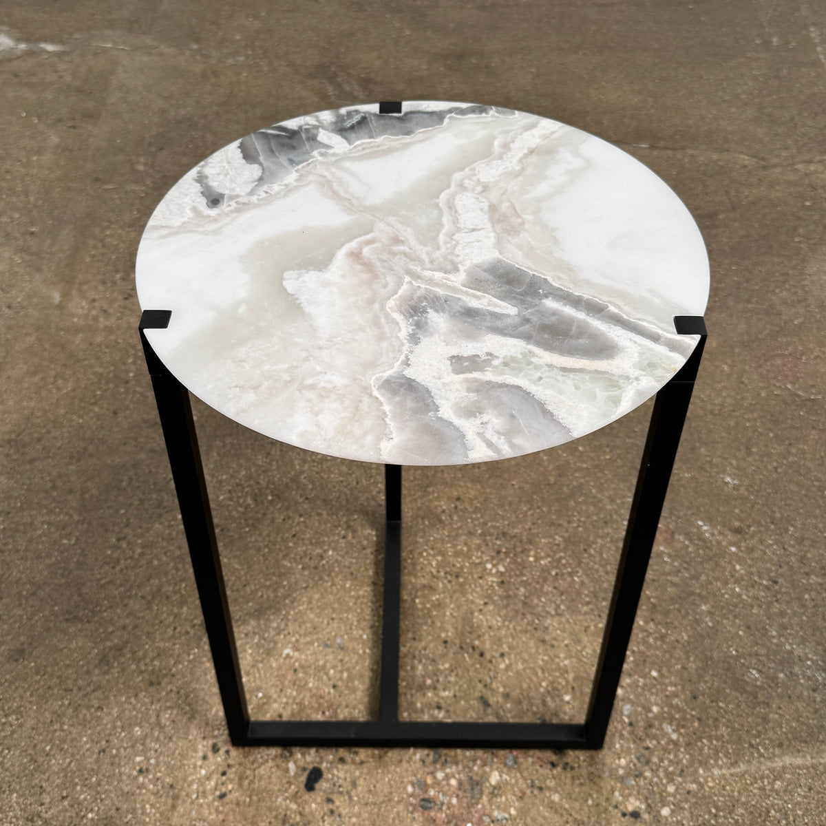 The Baxter Icaro Polar White Marble Accent Table - Small by Baxter showcases a sleek black metal base and a smooth Polar White marble top, photographed against a plain white background.