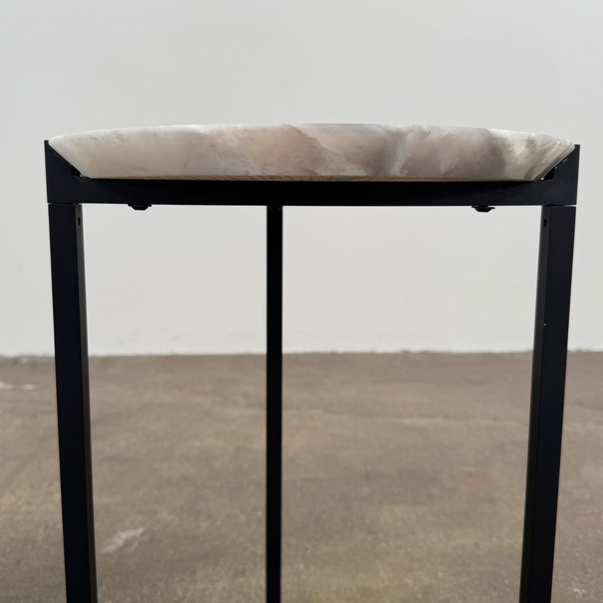 The Baxter Icaro Polar White Marble Accent Table - Small by Baxter showcases a sleek black metal base and a smooth Polar White marble top, photographed against a plain white background.