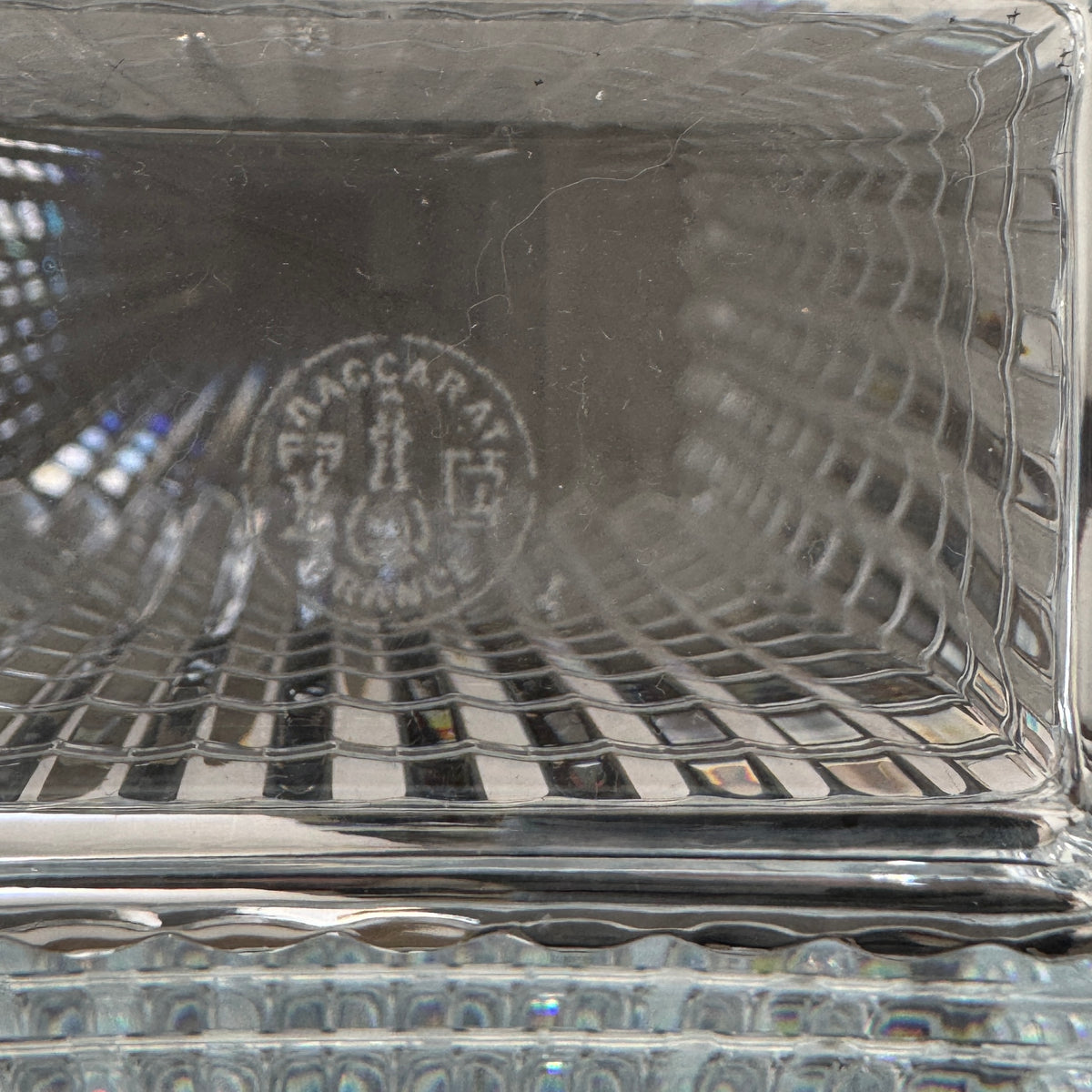 The Baccarat Eye Vase by Baccarat features clear glass with a geometric textured design, shown on a white pedestal and plain white background.