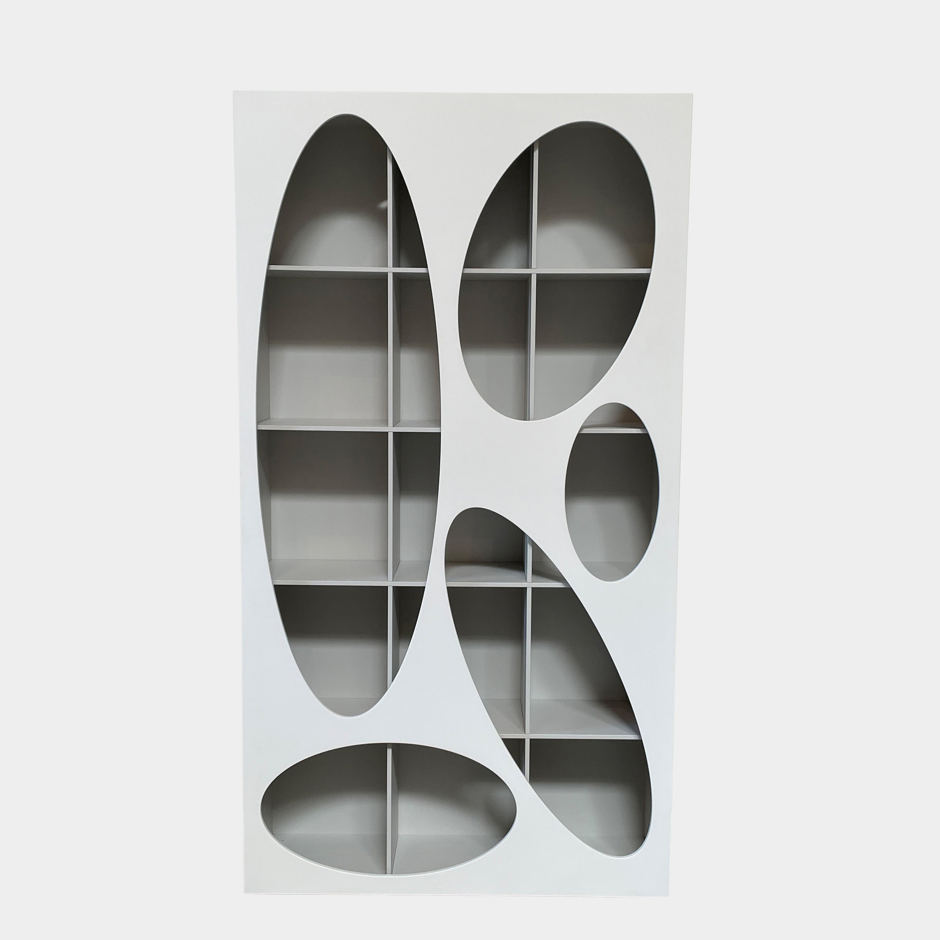 The Roche Bobois Denia Bookcase is a white bookshelf characterized by its abstract design, featuring multiple irregular oval cutouts, nine internal compartments, and integrated LED lighting, reminiscent of ROCHE BOBOIS styling.
