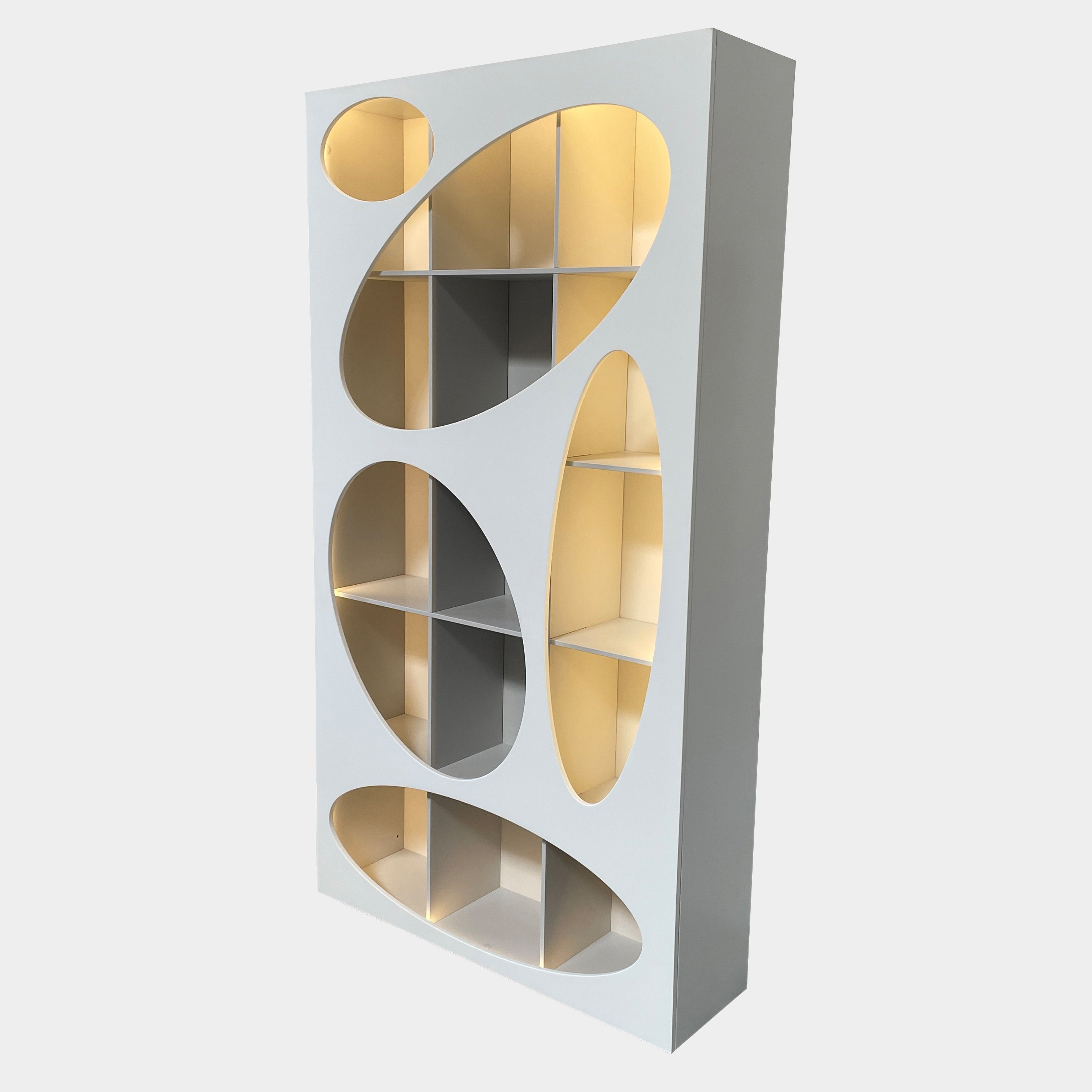 The Roche Bobois Denia Bookcase is a white bookshelf characterized by its abstract design, featuring multiple irregular oval cutouts, nine internal compartments, and integrated LED lighting, reminiscent of ROCHE BOBOIS styling.