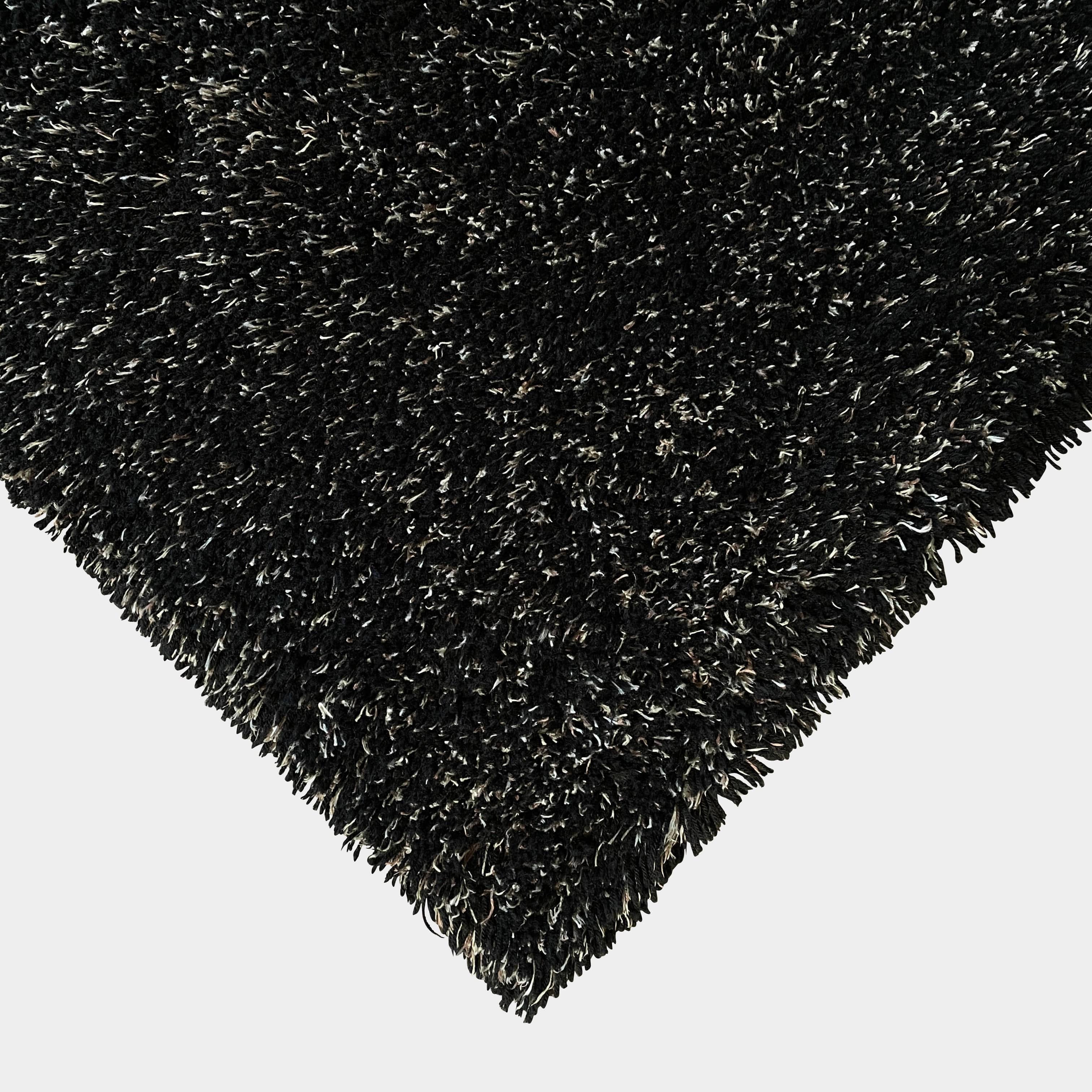 The Kasthall Moss Rug, designed by Gunnila Lagerhem Ullberg, is a hand-tufted rug featuring a shaggy black texture on a crisp white background.