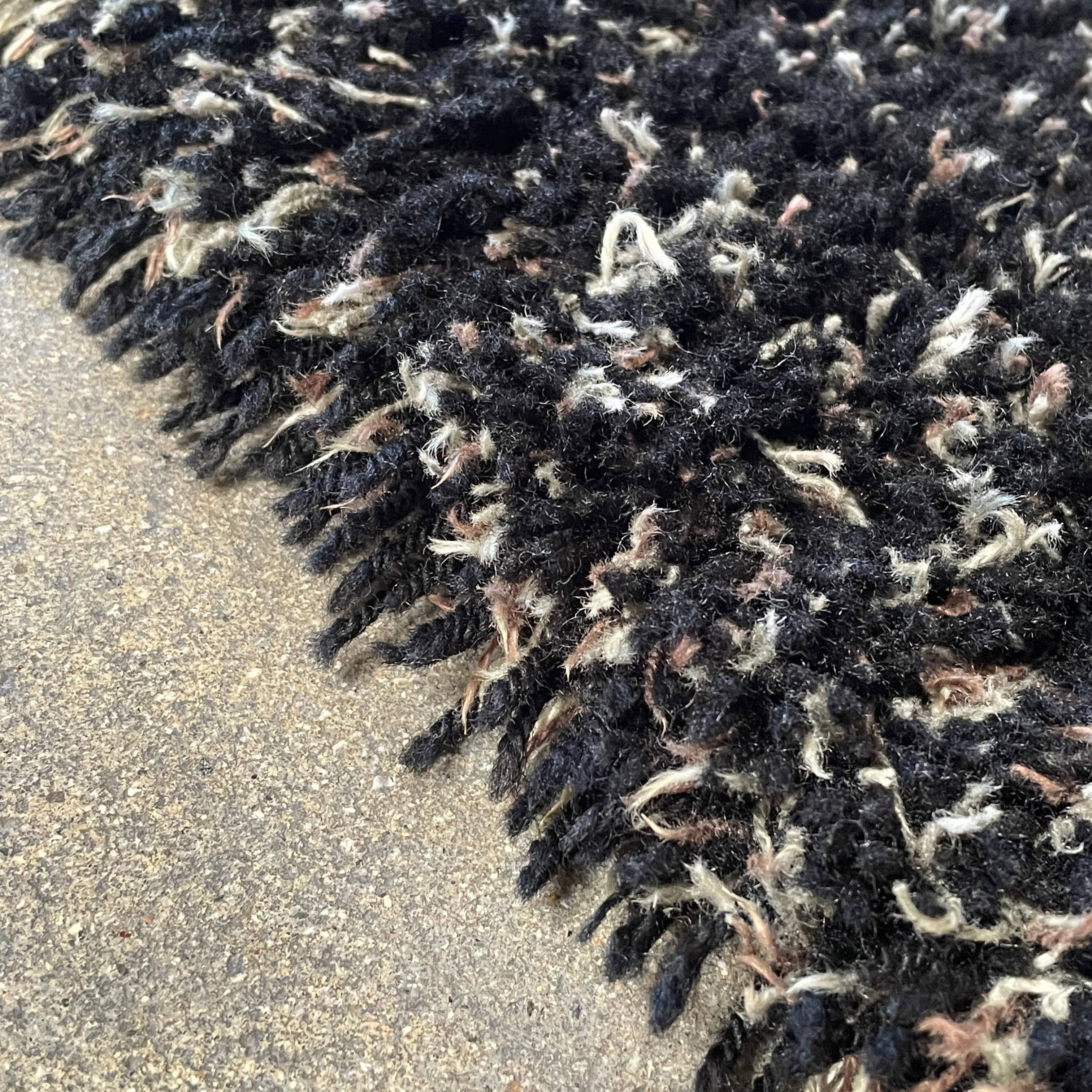 The Kasthall Moss Rug, designed by Gunnila Lagerhem Ullberg, is a hand-tufted rug featuring a shaggy black texture on a crisp white background.