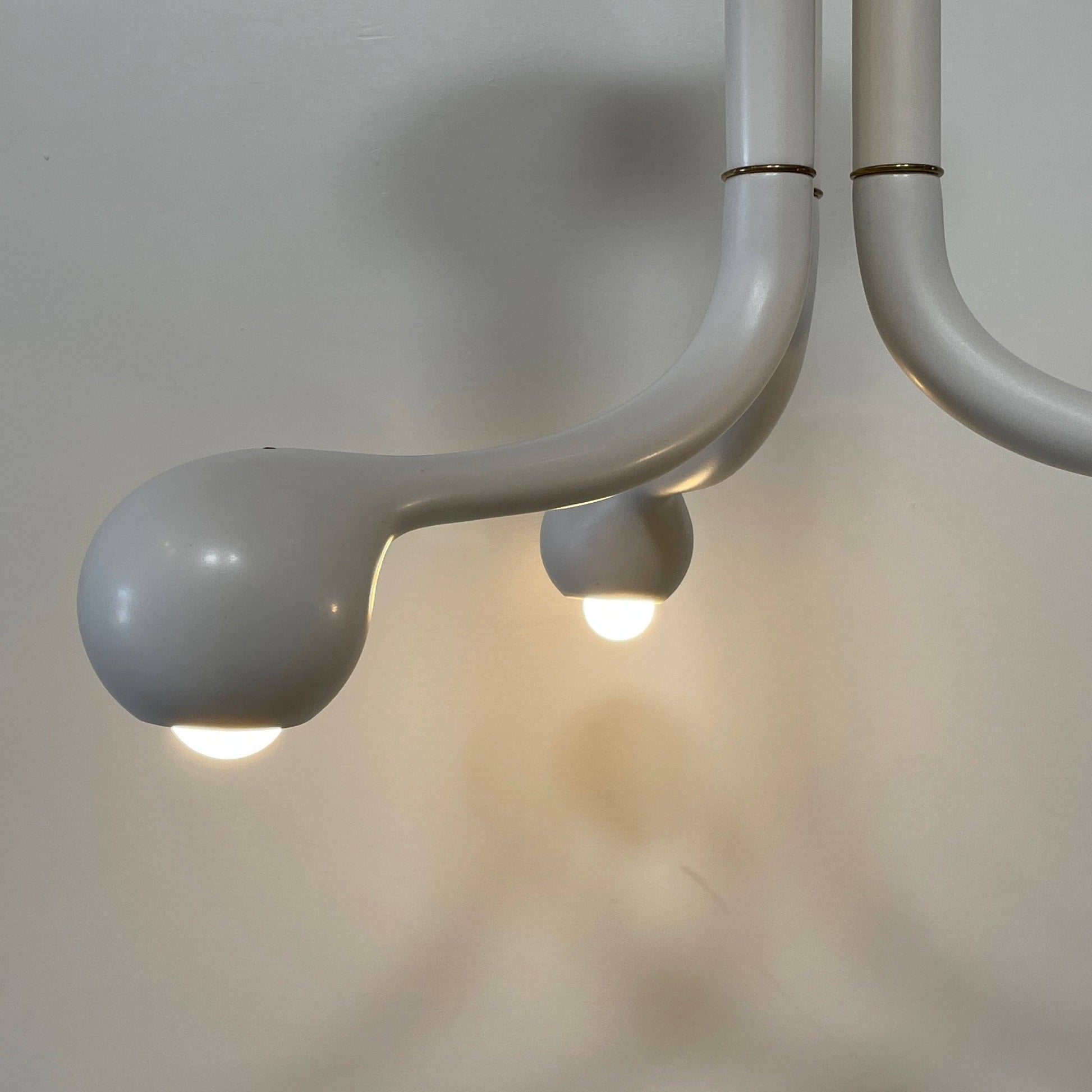 A white, three-legged stand with rounded feet and a flat top against a plain background, reminiscent of the elegant aesthetic found in Entler Studio's 3-Globe Ceiling Light creations.