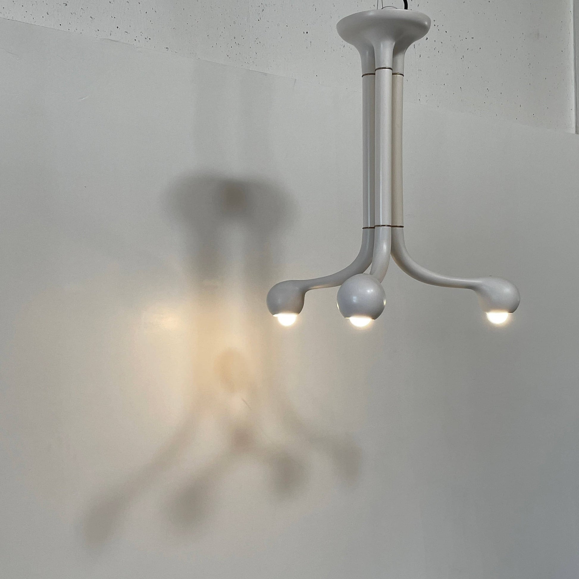 A white, three-legged stand with rounded feet and a flat top against a plain background, reminiscent of the elegant aesthetic found in Entler Studio's 3-Globe Ceiling Light creations.