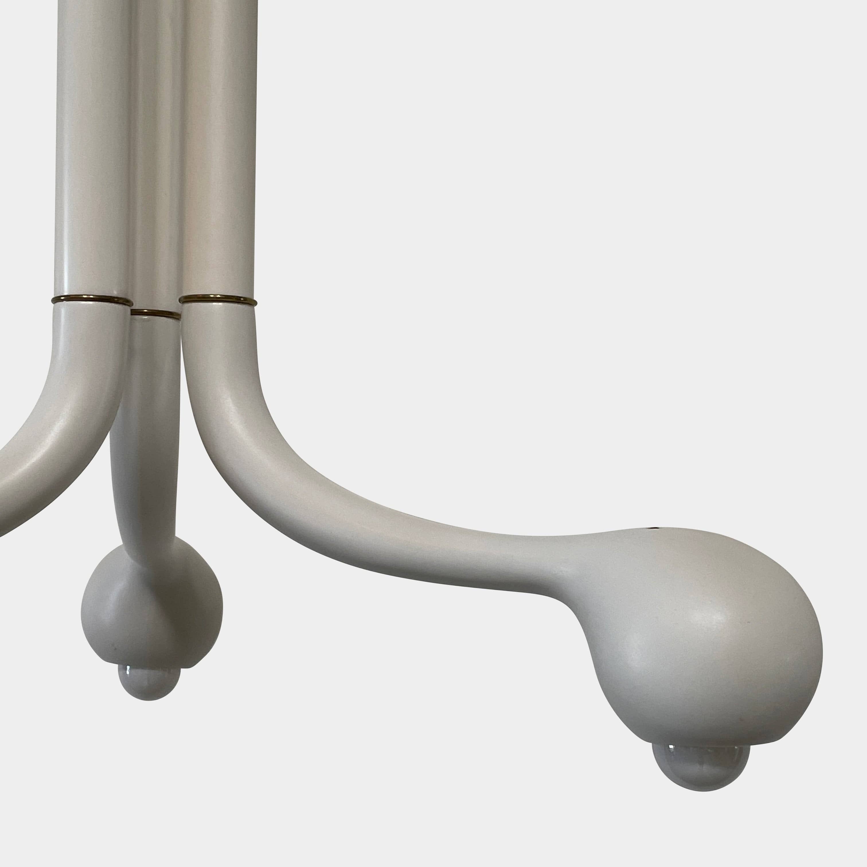 A white, three-legged stand with rounded feet and a flat top against a plain background, reminiscent of the elegant aesthetic found in Entler Studio's 3-Globe Ceiling Light creations.
