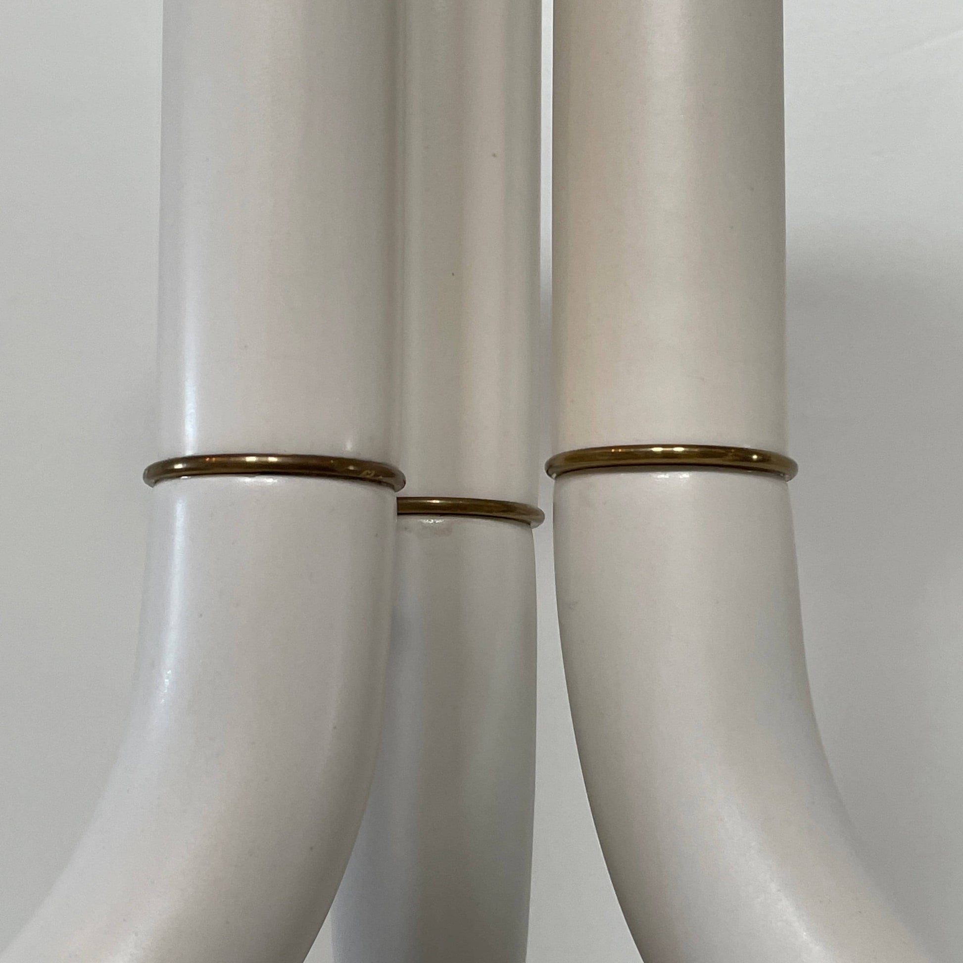 A white, three-legged stand with rounded feet and a flat top against a plain background, reminiscent of the elegant aesthetic found in Entler Studio's 3-Globe Ceiling Light creations.