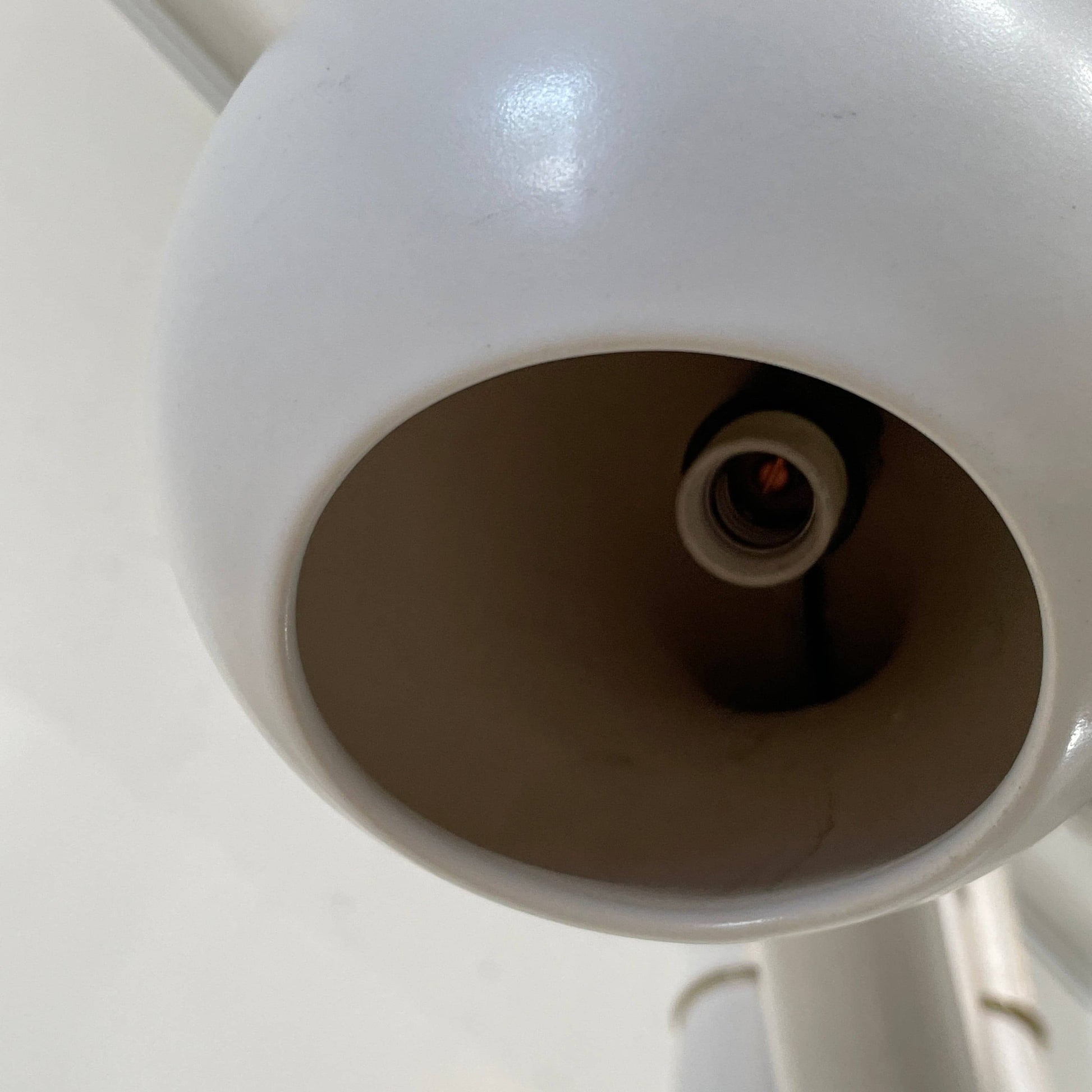 A white, three-legged stand with rounded feet and a flat top against a plain background, reminiscent of the elegant aesthetic found in Entler Studio's 3-Globe Ceiling Light creations.