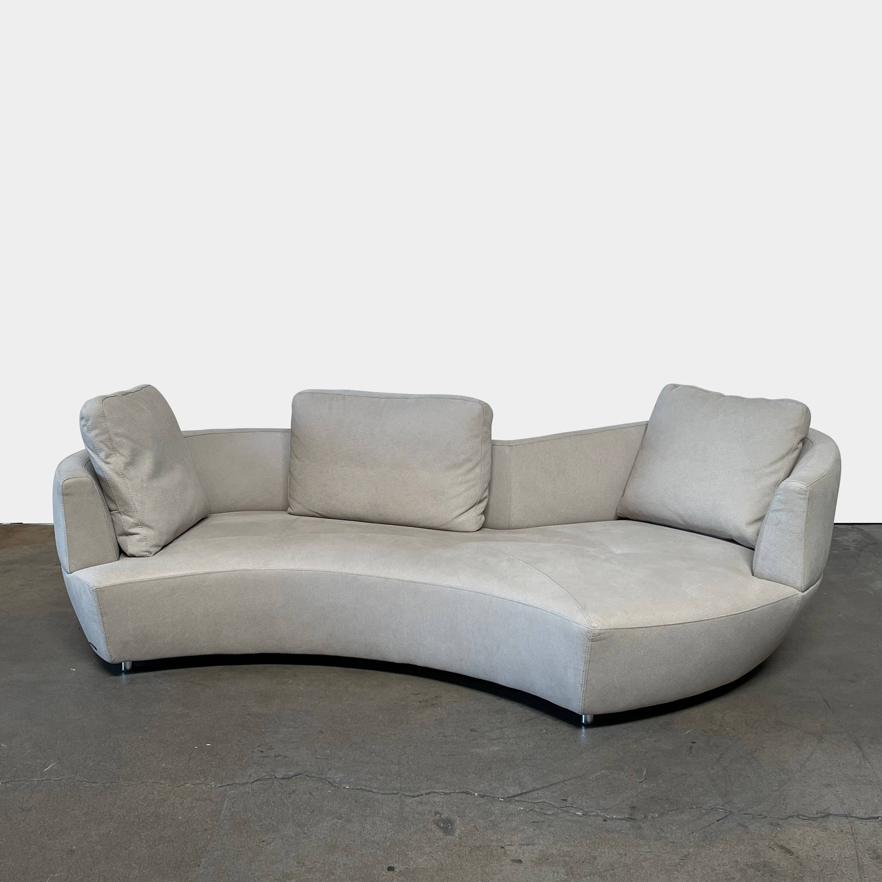 A Roche Bobois Digital Sofa and Ottoman, featuring a curved grey sectional design with three cushions and an additional round ottoman, set against a plain white background.
