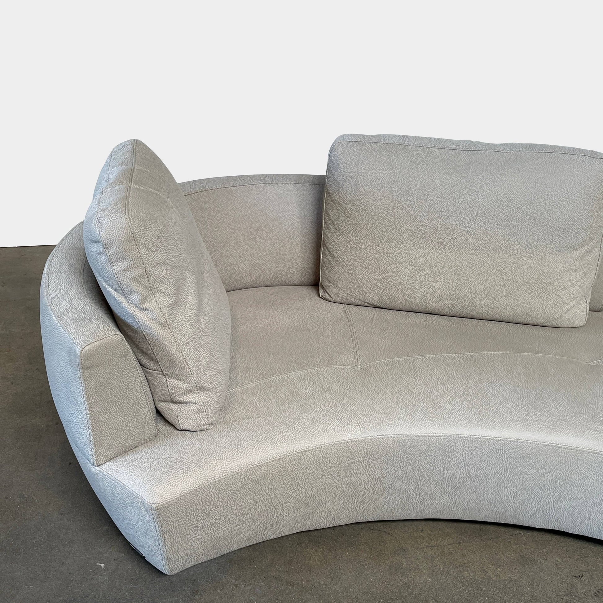A Roche Bobois Digital Sofa and Ottoman, featuring a curved grey sectional design with three cushions and an additional round ottoman, set against a plain white background.