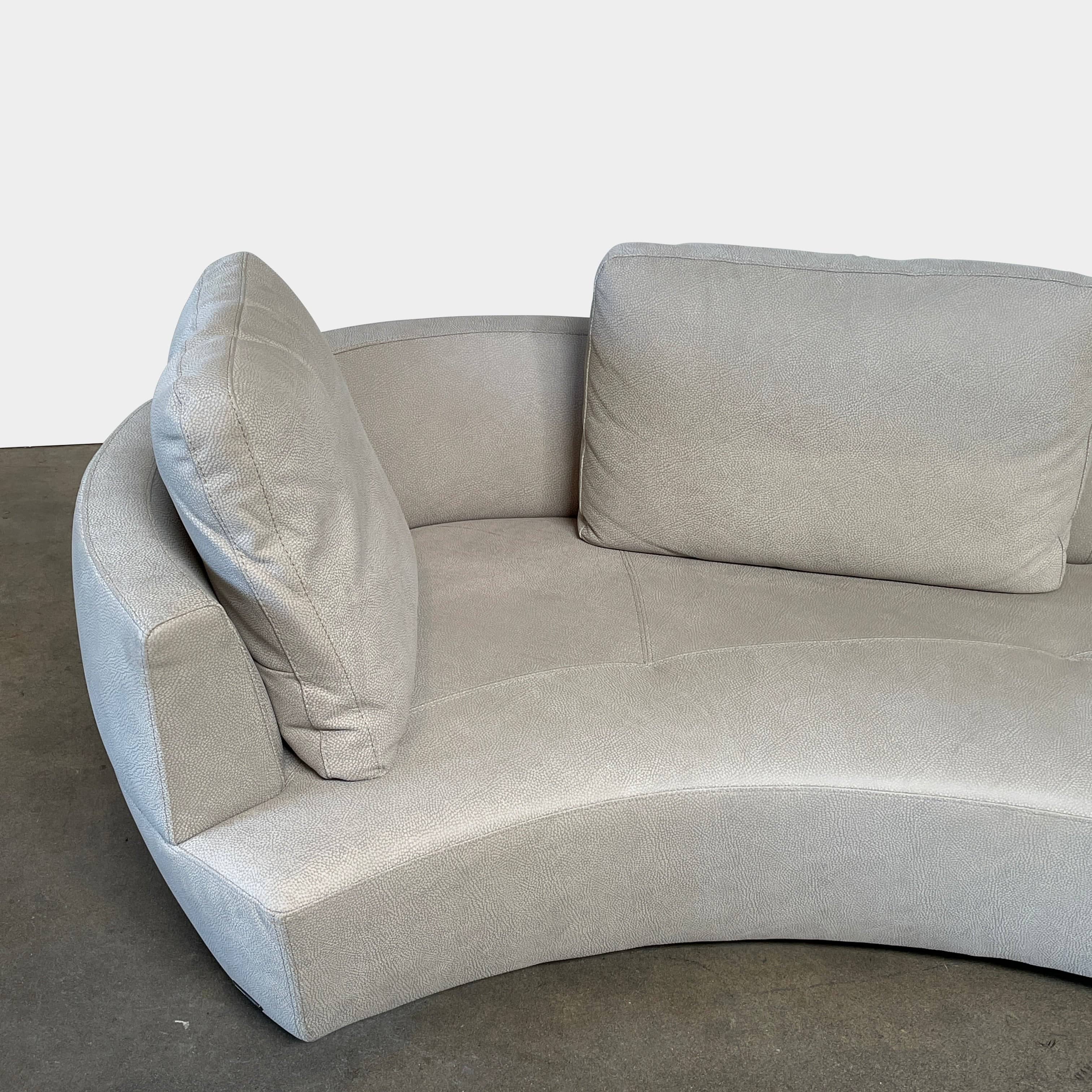 A Roche Bobois Digital Sofa and Ottoman, featuring a curved grey sectional design with three cushions and an additional round ottoman, set against a plain white background.