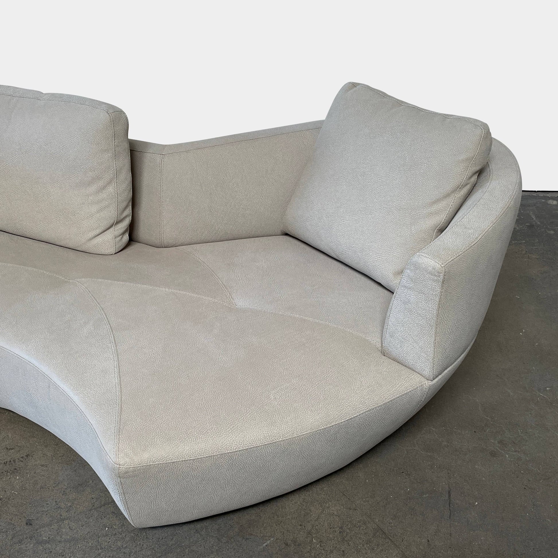 A Roche Bobois Digital Sofa and Ottoman, featuring a curved grey sectional design with three cushions and an additional round ottoman, set against a plain white background.