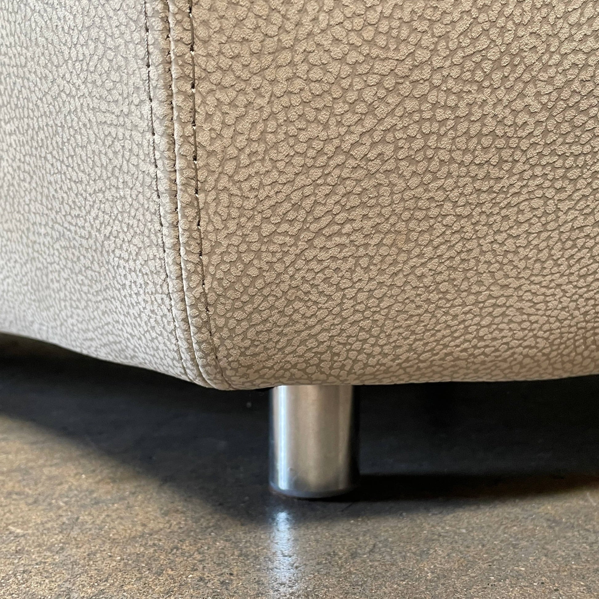 A Roche Bobois Digital Sofa and Ottoman, featuring a curved grey sectional design with three cushions and an additional round ottoman, set against a plain white background.