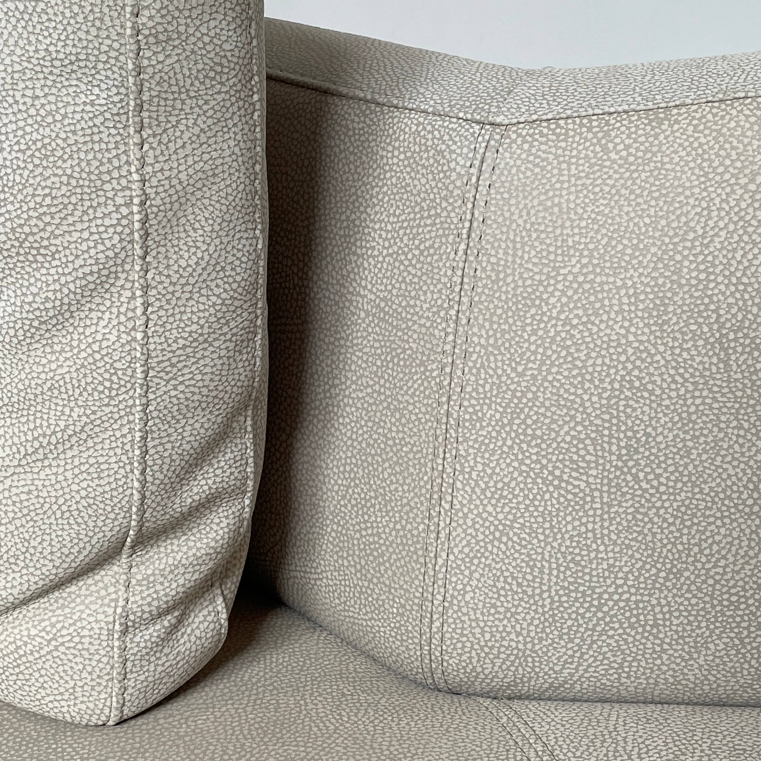 A Roche Bobois Digital Sofa and Ottoman, featuring a curved grey sectional design with three cushions and an additional round ottoman, set against a plain white background.