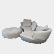 A Roche Bobois Digital Sofa and Ottoman, featuring a curved grey sectional design with three cushions and an additional round ottoman, set against a plain white background.