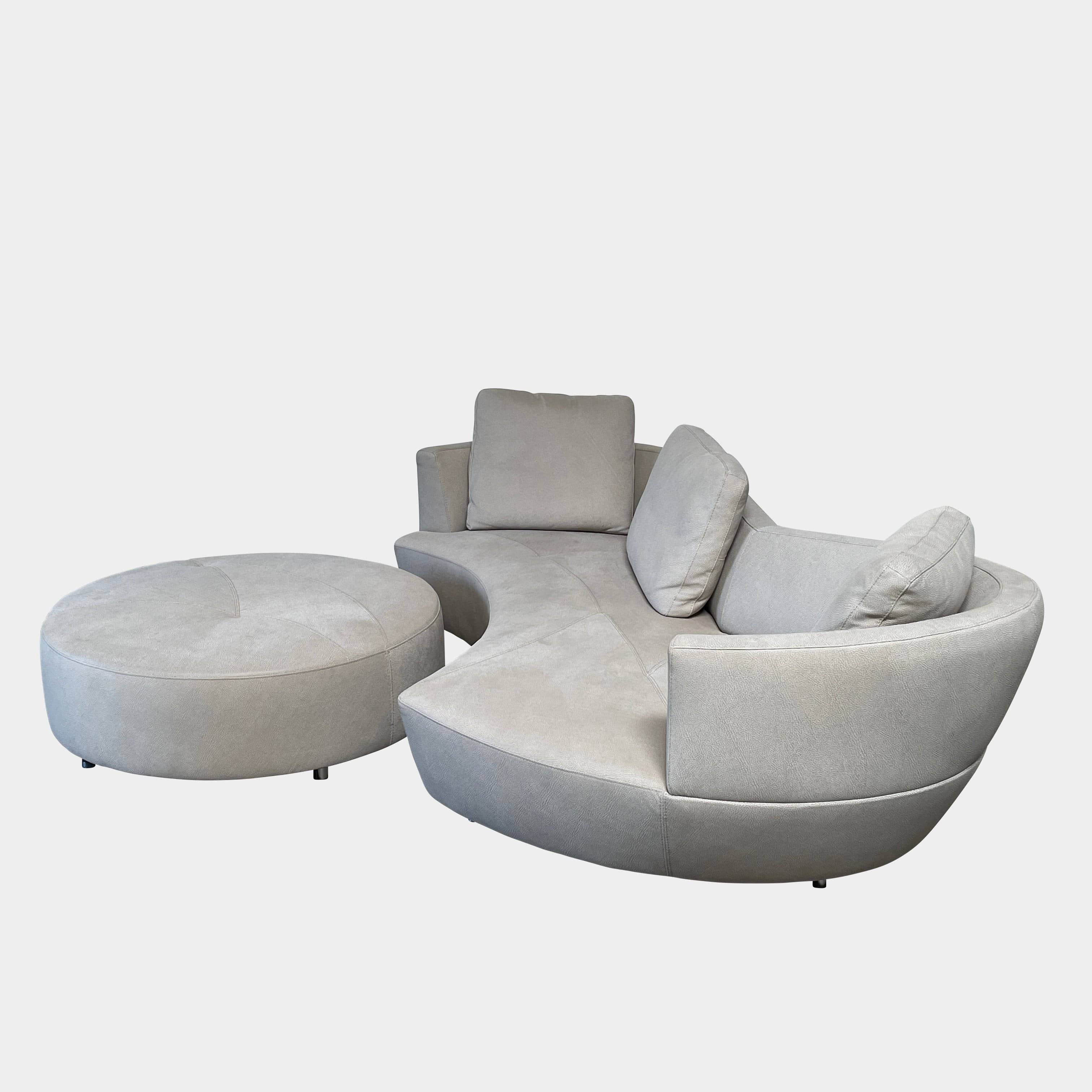 A Roche Bobois Digital Sofa and Ottoman, featuring a curved grey sectional design with three cushions and an additional round ottoman, set against a plain white background.