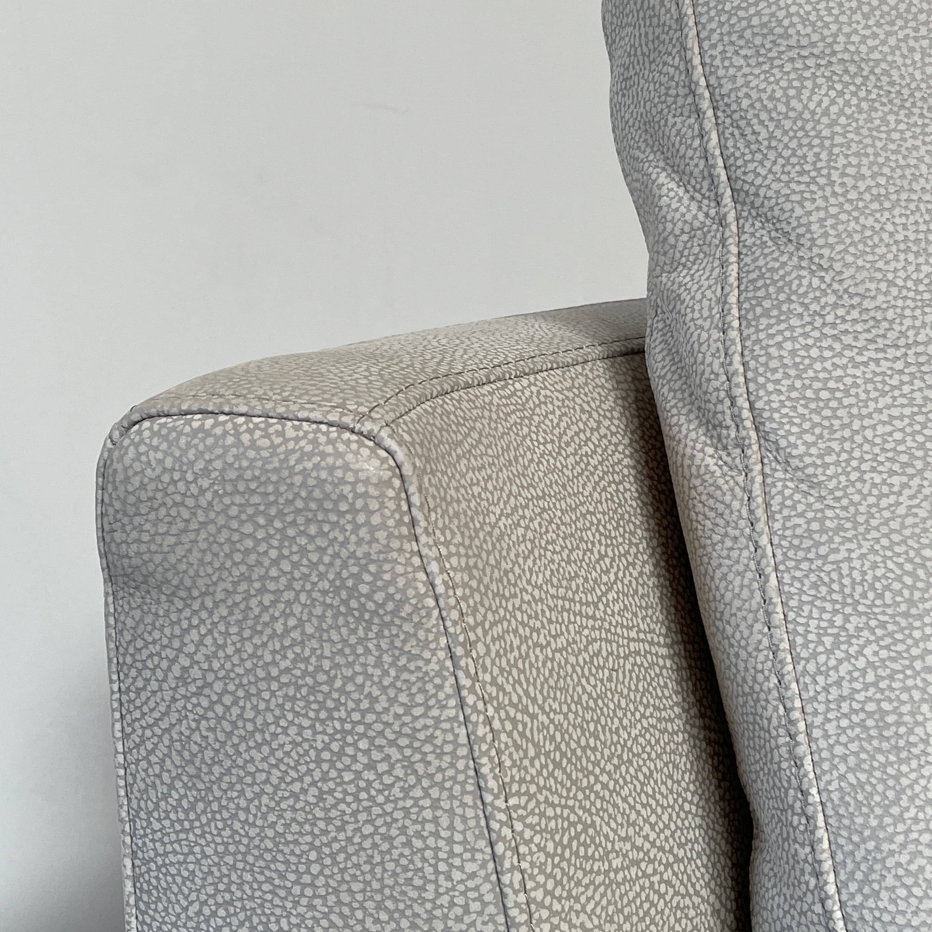 A Roche Bobois Digital Sofa and Ottoman, featuring a curved grey sectional design with three cushions and an additional round ottoman, set against a plain white background.