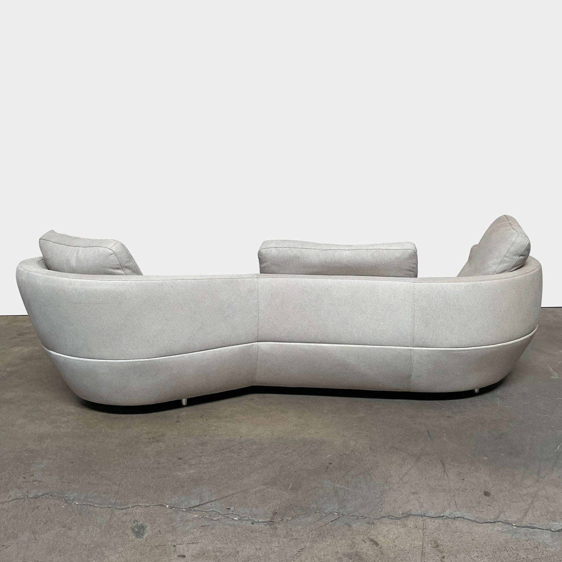A Roche Bobois Digital Sofa and Ottoman, featuring a curved grey sectional design with three cushions and an additional round ottoman, set against a plain white background.