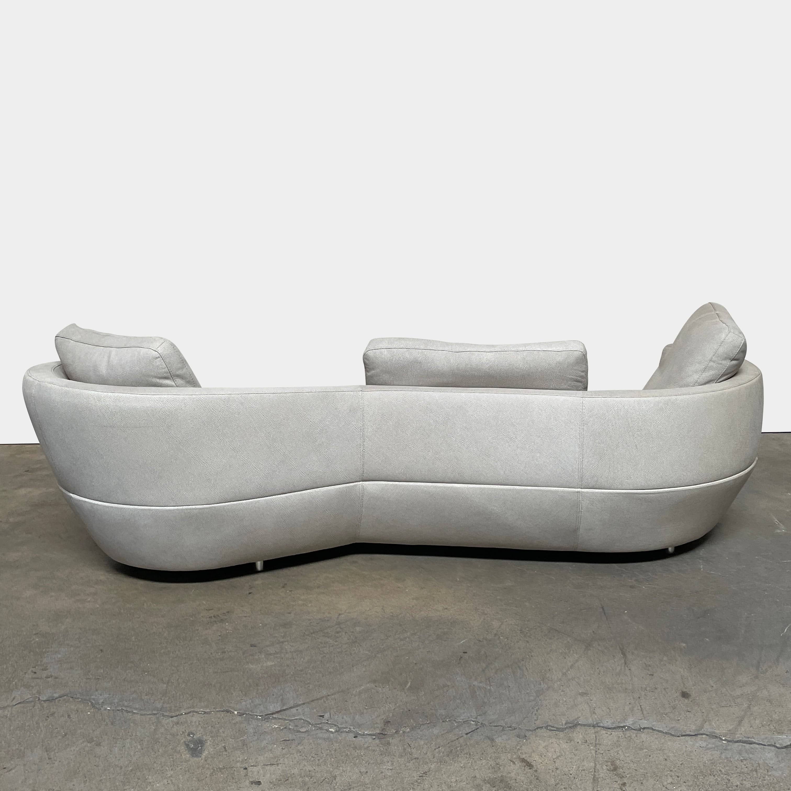 A Roche Bobois Digital Sofa and Ottoman, featuring a curved grey sectional design with three cushions and an additional round ottoman, set against a plain white background.