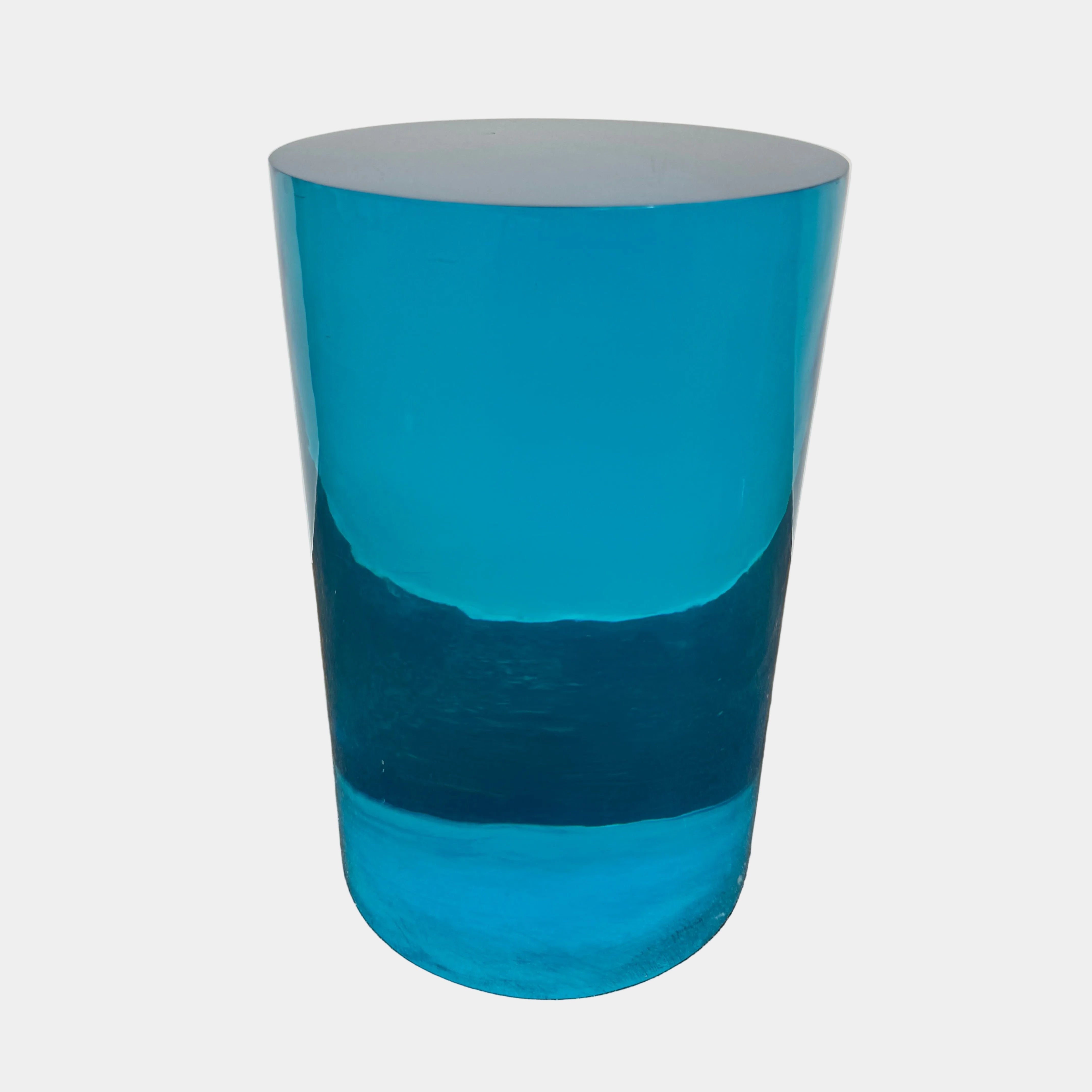 The Jonathan Adler blue acrylic cylindrical table stands upright on a white background, featuring smooth sides and a flat top that evoke the brand’s modern, chic design aesthetic.