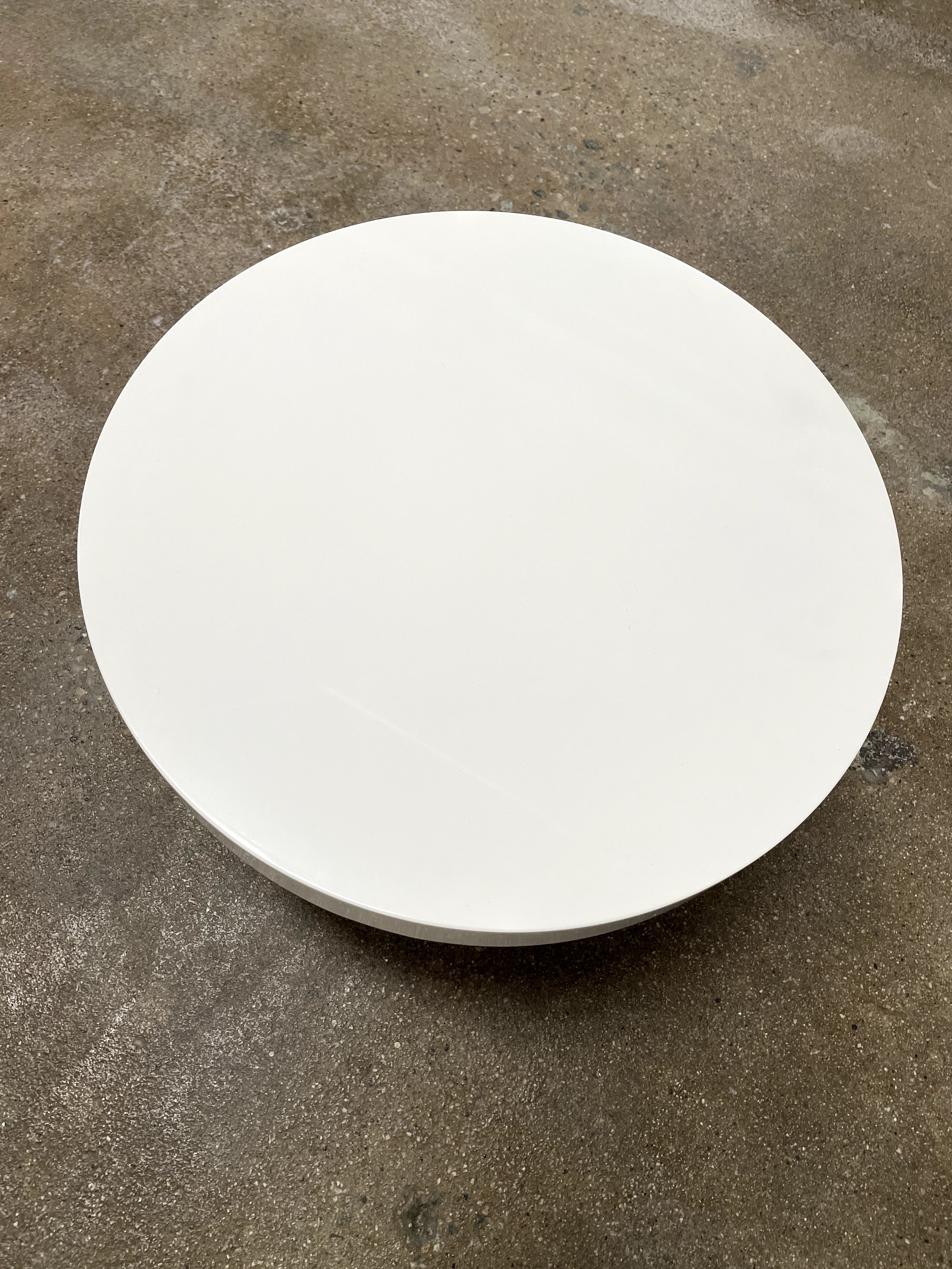 The Ligne Roset White Lacquer Needle Table features a sleek lacquer top and four slender metal legs, perfectly exemplifying modern minimalism against a plain background.