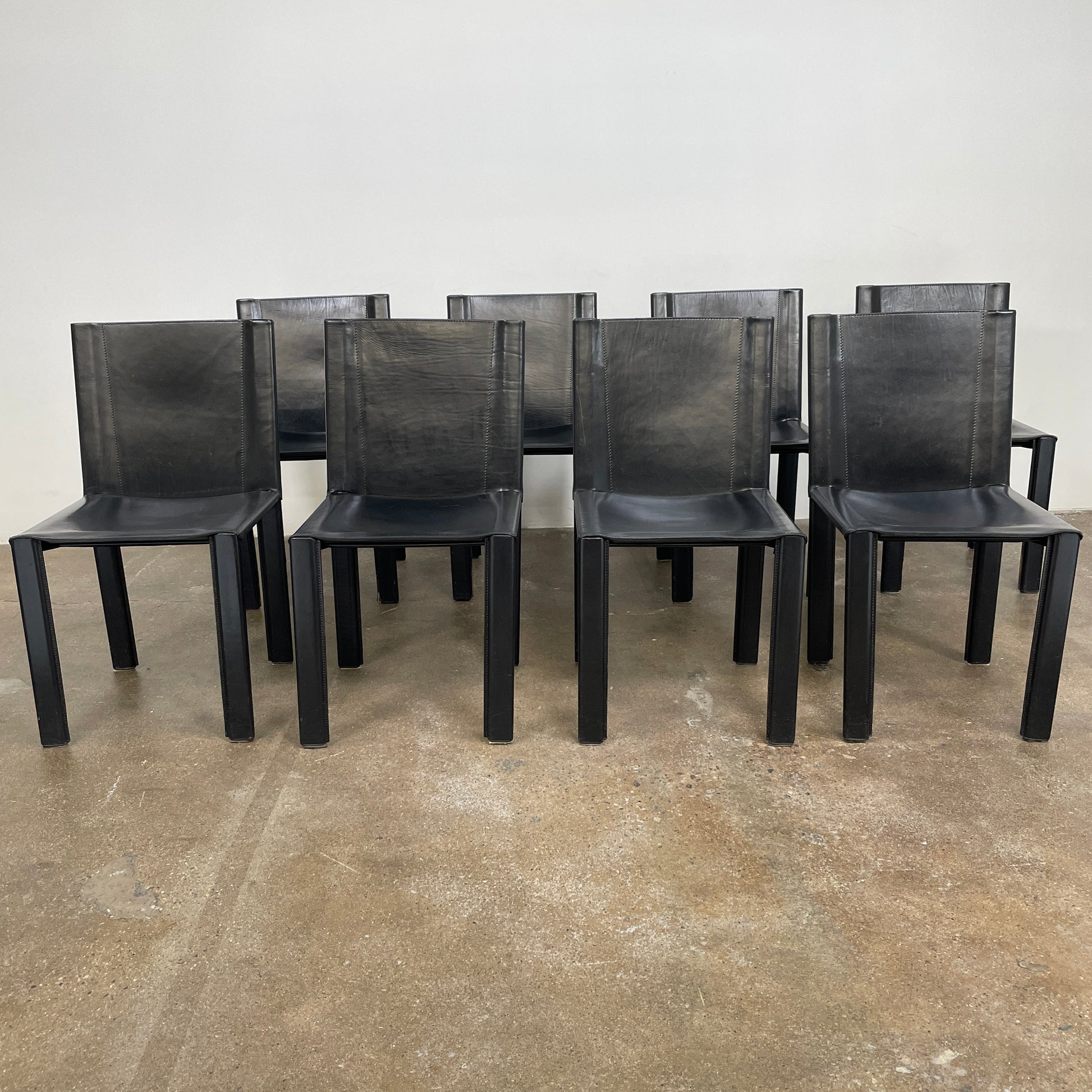 Eight Vintage Matteo Grassi 'Coral' dining chairs, showcasing a sleek black finish, are arranged in two rows on a pristine white background.