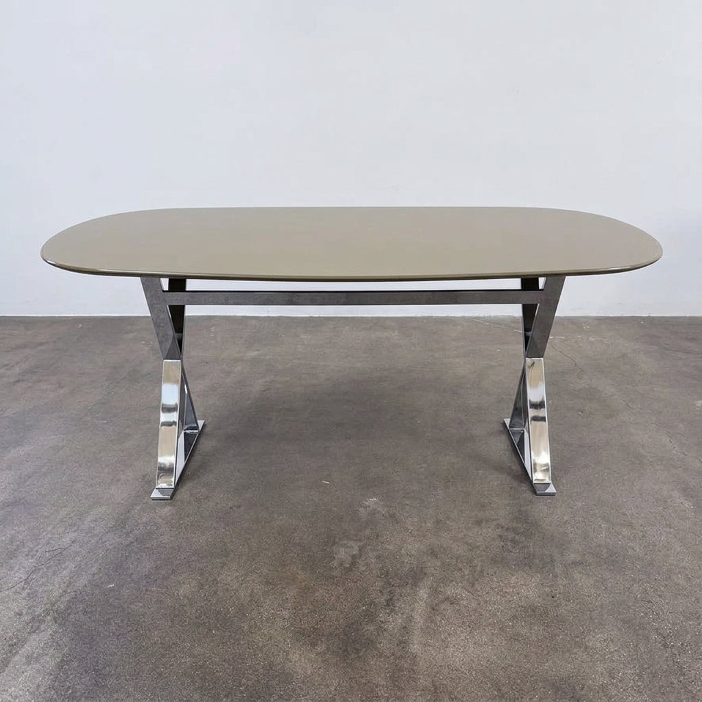 Maxalto Pathos dining table featuring an oval dark top and a contemporary elegant X-shaped chrome frame.