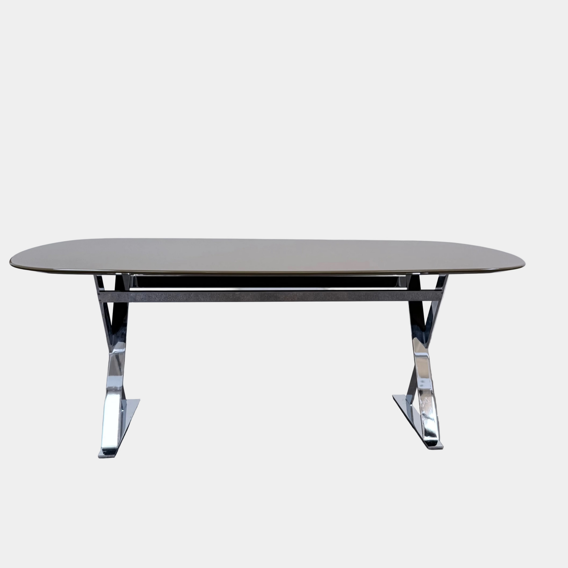 Maxalto Pathos dining table with an oval beige top and a contemporary chrome X-shaped frame.