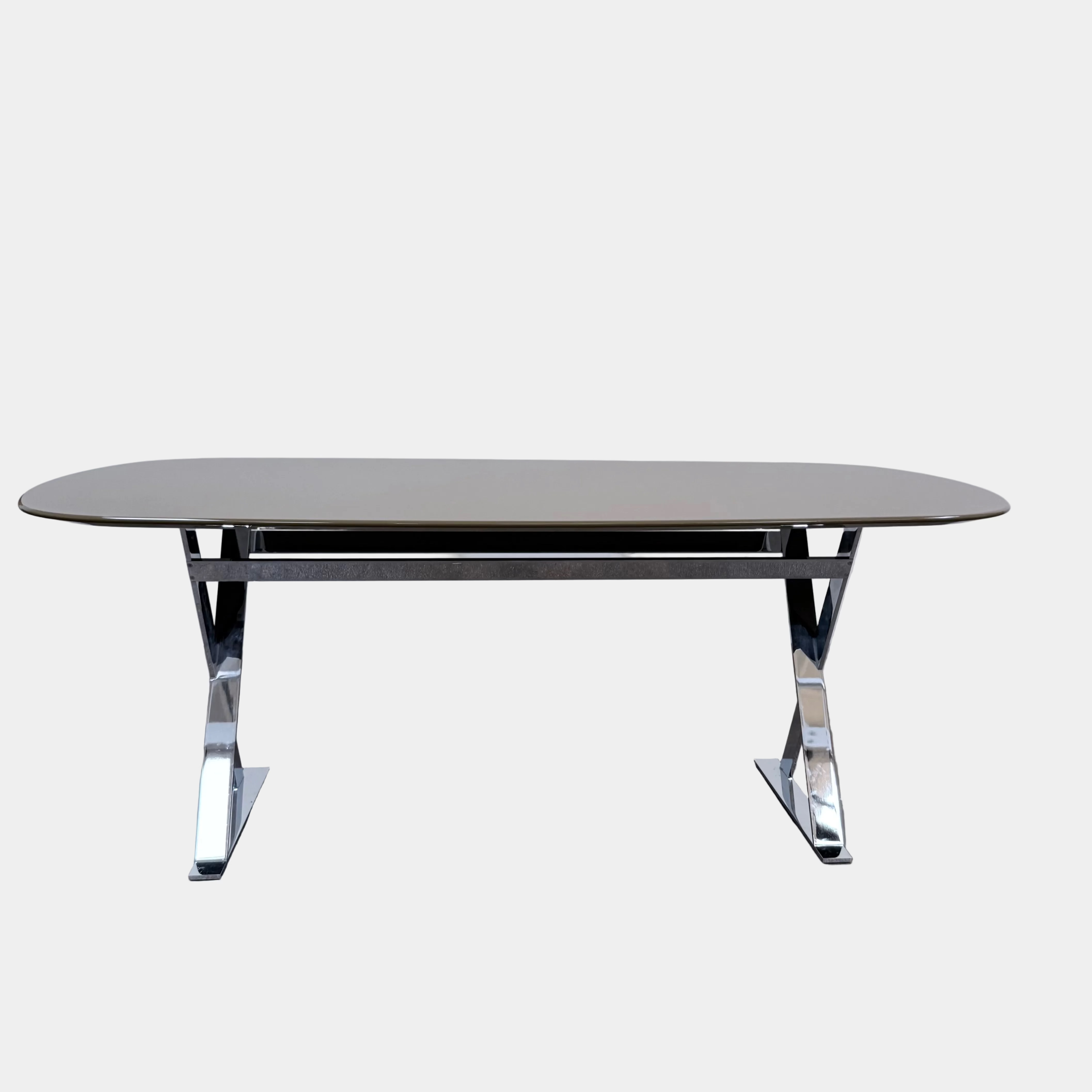 Maxalto Pathos dining table with an oval beige top and a contemporary chrome X-shaped frame.