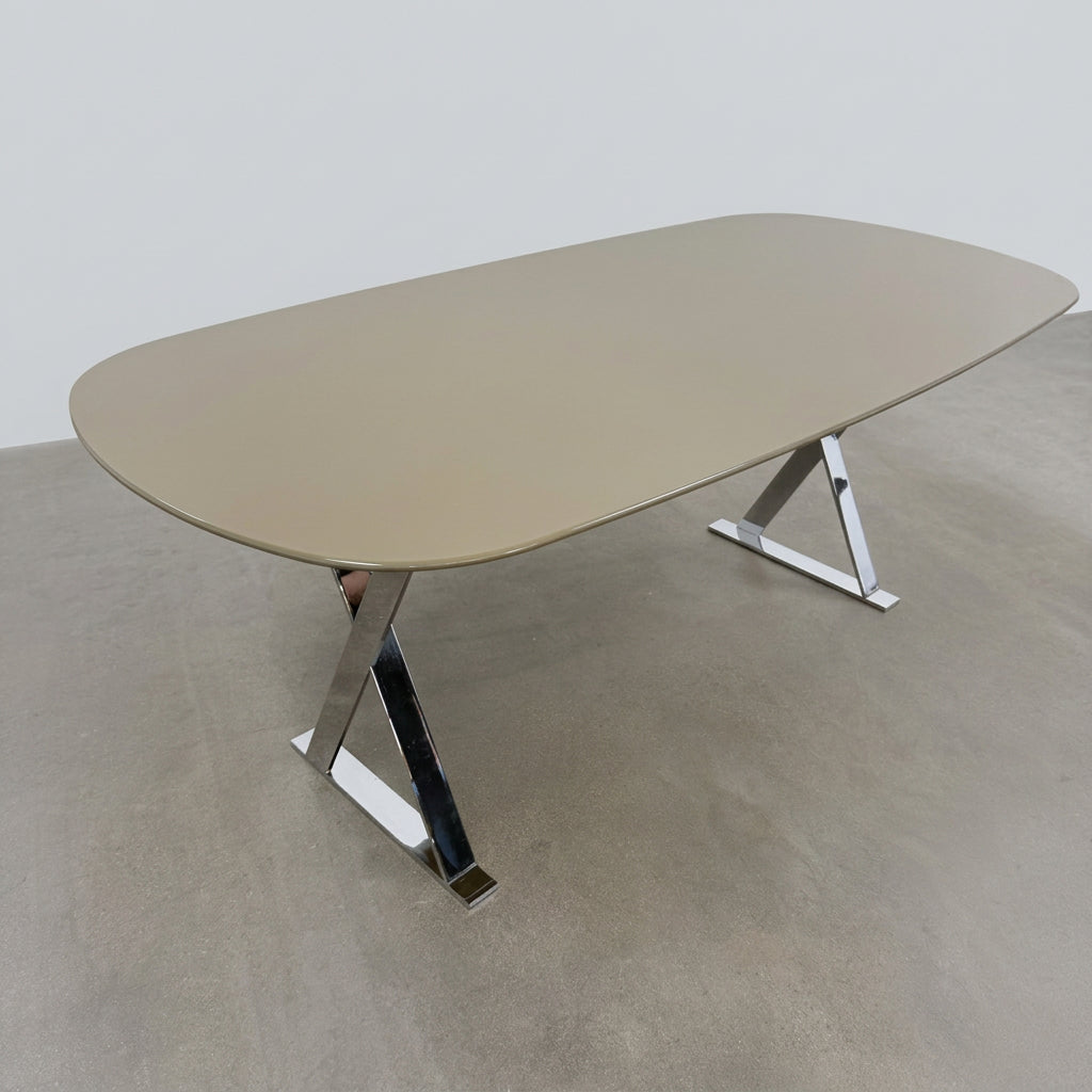 Maxalto Pathos dining table featuring an oval dark top and a contemporary elegant X-shaped chrome frame.