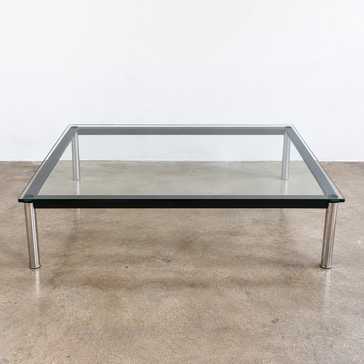 Cassina LC10 Low Glass Table featuring a low, square glass top, black frame, and four tubular metal legs in a mid-century modern style.