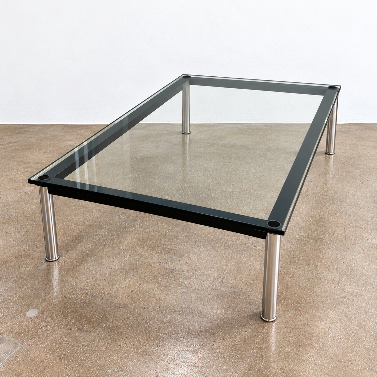 Cassina LC10 Low Glass Table featuring a low, square glass top, black frame, and four tubular metal legs in a mid-century modern style.