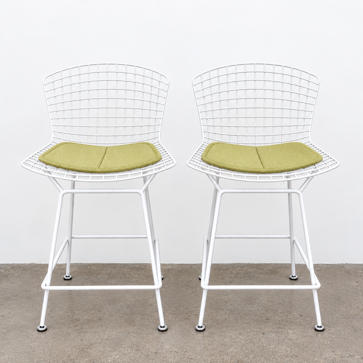 Two white Knoll Harry Bertoia Wire Counter Stools with light green seat cushions.