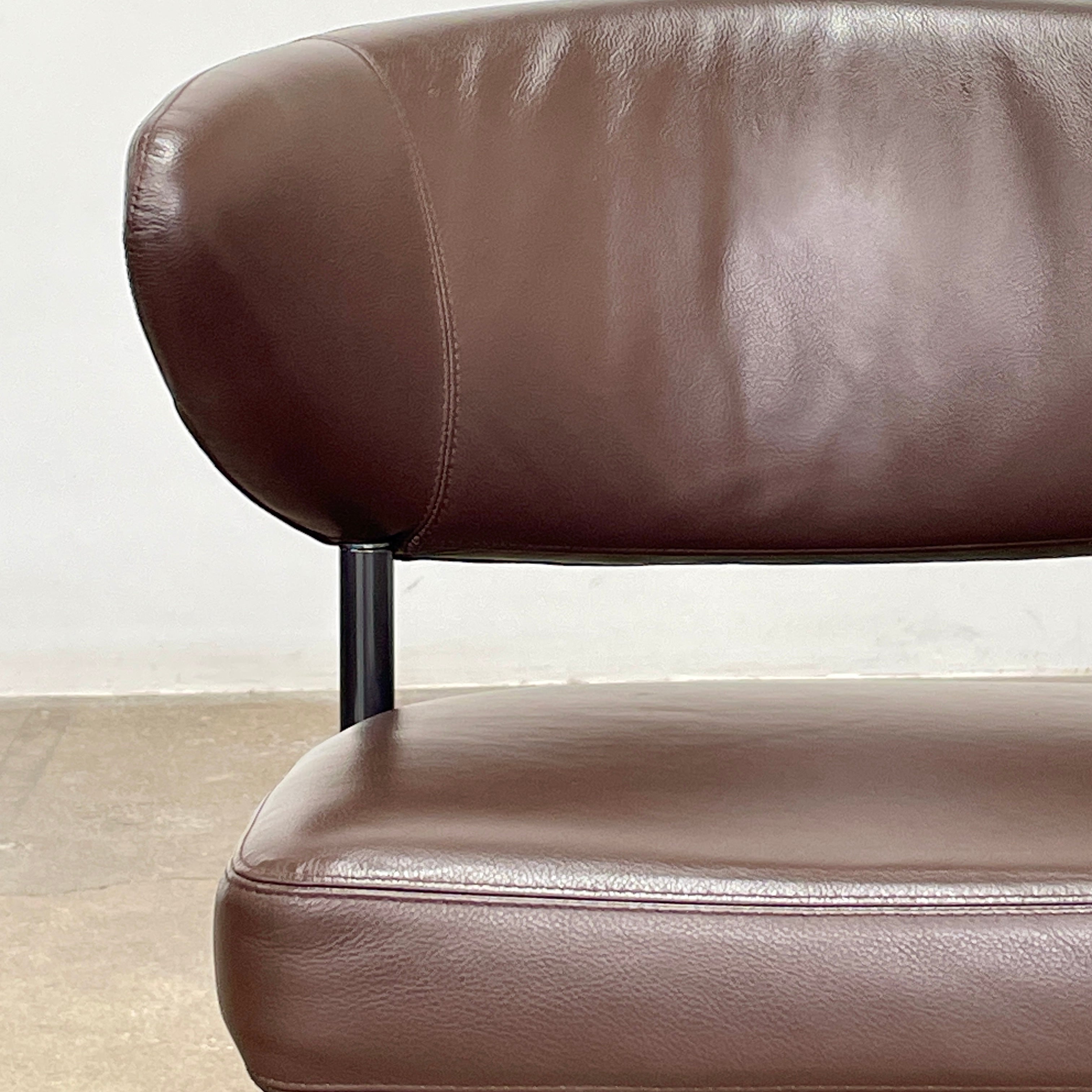 A set of six Minotti Mills Dining Chairs, featuring Scandinavian design with brown leather upholstery and black metal legs, is arranged in a staggered formation against a plain background.