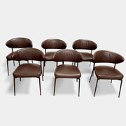A set of six Minotti Mills Dining Chairs, featuring Scandinavian design with brown leather upholstery and black metal legs, is arranged in a staggered formation against a plain background.