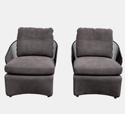 A set of two Minotti Colette Lounge Chairs by Minotti is displayed side by side against a plain white background. Each chair showcases luxurious gray nubuck leather upholstery and sleek black metal armrests, elegantly capturing the timeless mid-century silhouette characteristic of the iconic design.