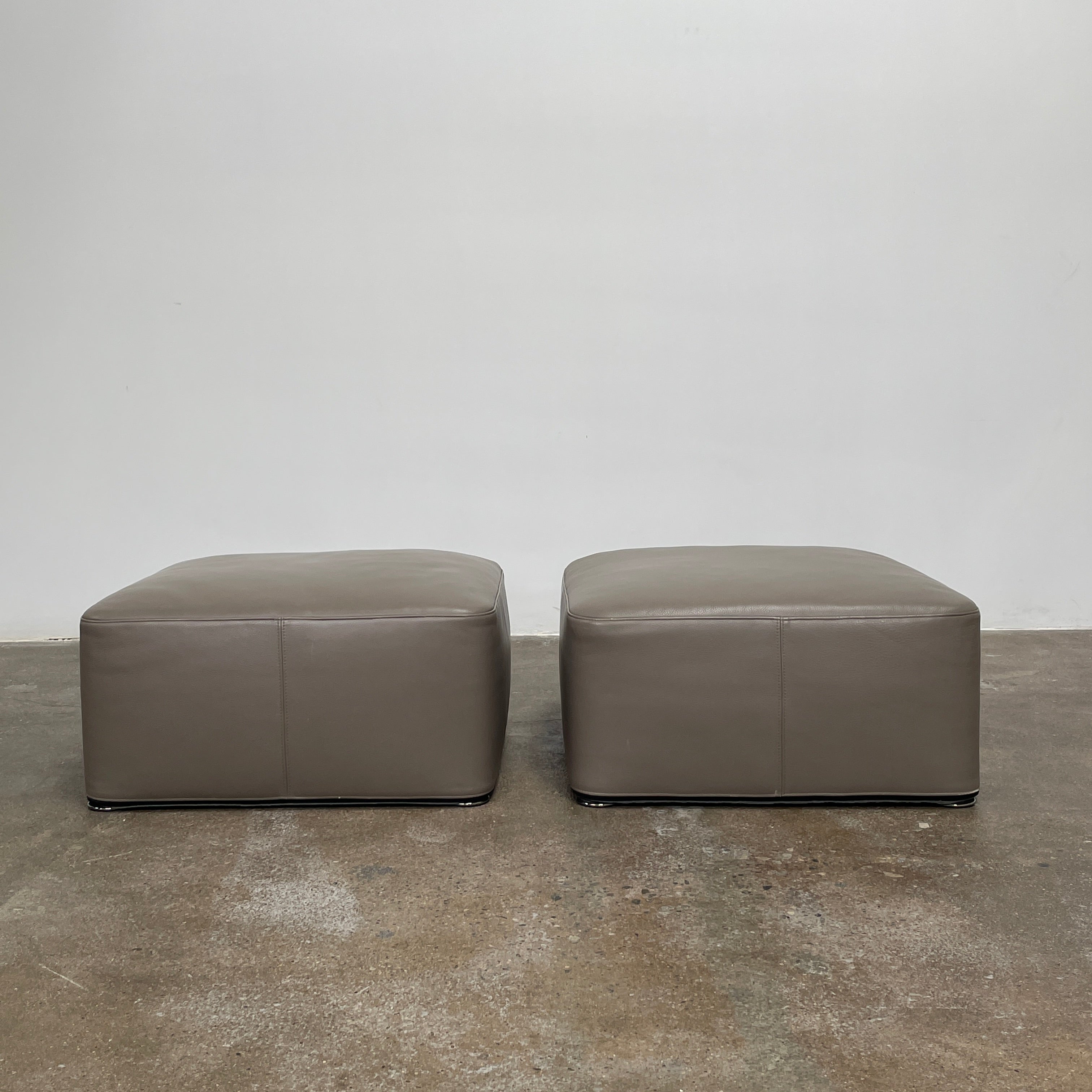 The Minotti Davis Leather Ottoman is a luxurious square piece crafted from rich brown leather, beautifully contrasted with a pristine white background.