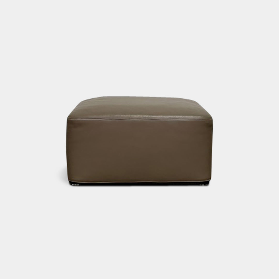 The Minotti Davis Leather Ottoman is a luxurious square piece crafted from rich brown leather, beautifully contrasted with a pristine white background.
