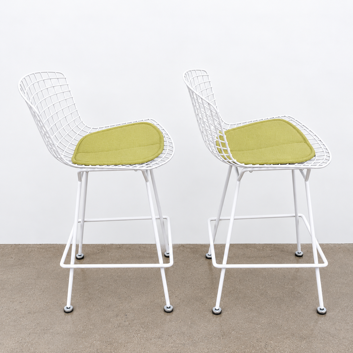 Two white Knoll Harry Bertoia Wire Counter Stools with light green seat cushions.
