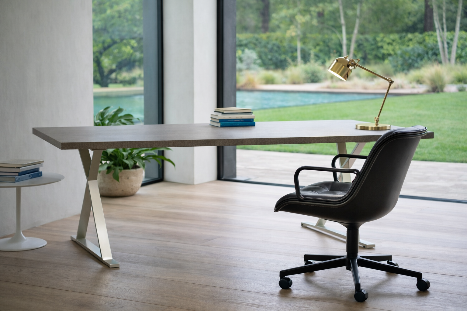A DWR Pollock Executive Chair with a chrome frame and five wheels is shown from the back, set on a concrete floor against a plain white wall.