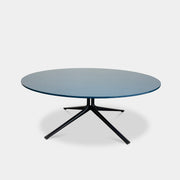 The Poliform Mondrian Lacquered Coffee Table showcases a round blue top with a black, four-legged metal base against a white background.