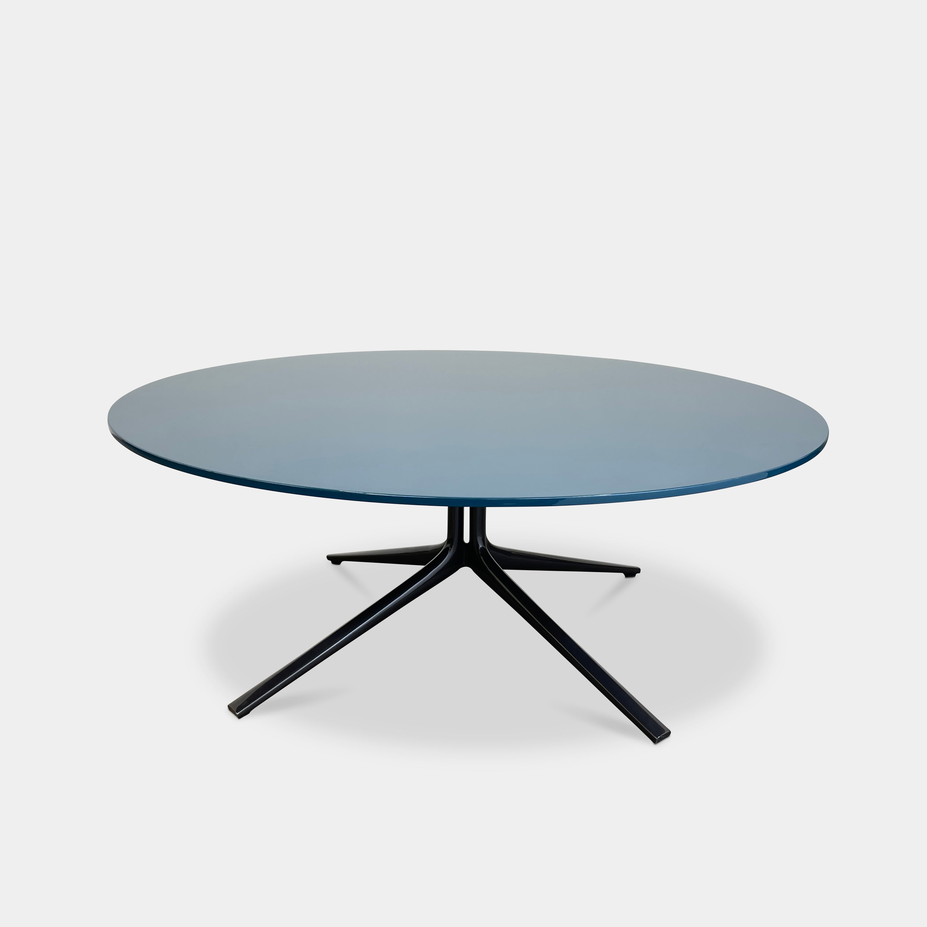 The Poliform Mondrian Lacquered Coffee Table showcases a round blue top with a black, four-legged metal base against a white background.