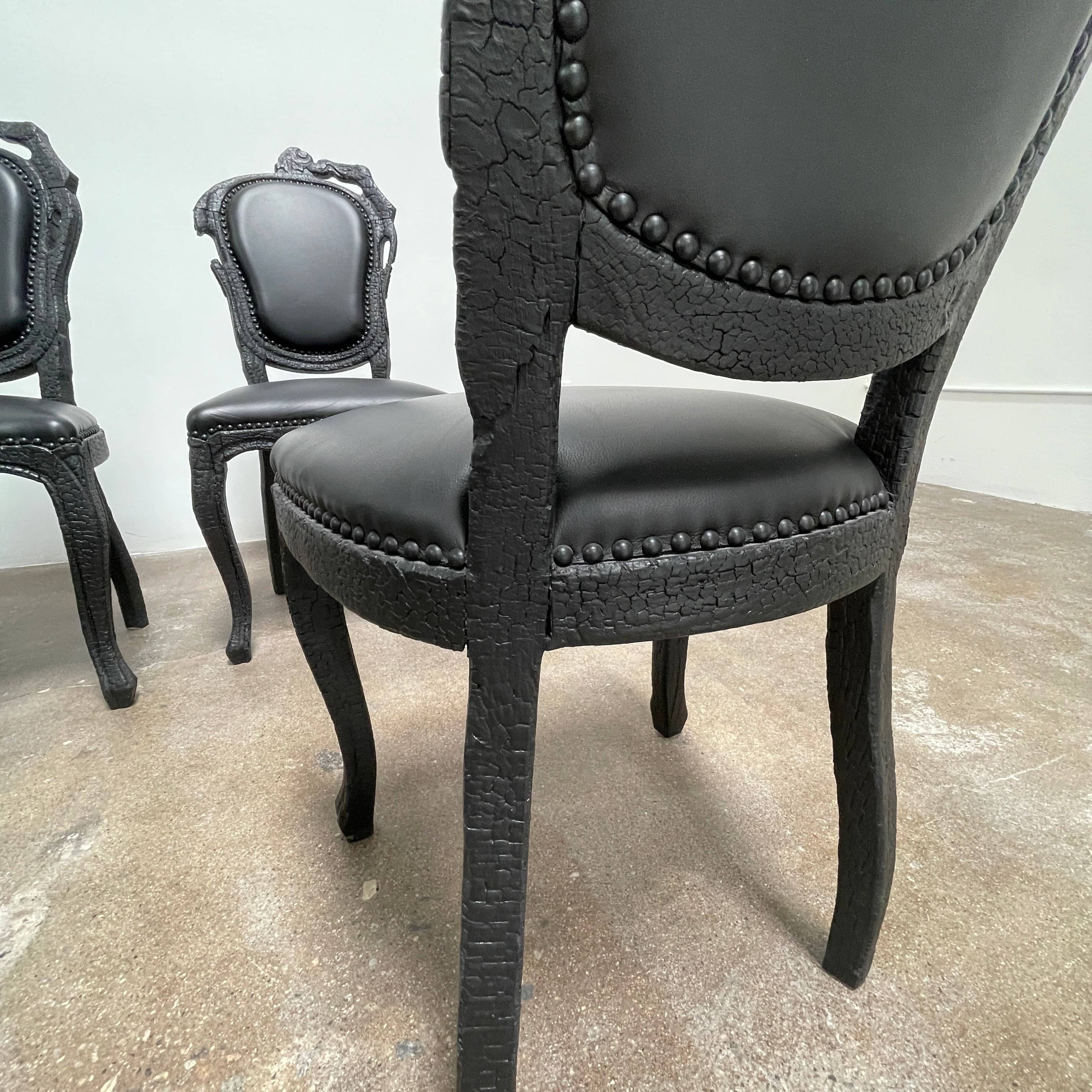 A set of seven Moooi Smoke Dining Side Chairs, crafted by Moooi in an ornate black finish with leather upholstery and cushioned seats and backs, arranged in two rows against a plain white background.