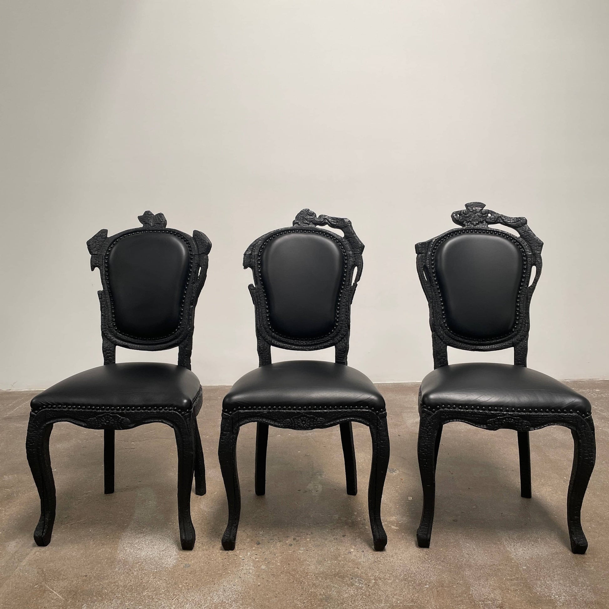 A set of seven Moooi Smoke Dining Side Chairs, crafted by Moooi in an ornate black finish with leather upholstery and cushioned seats and backs, arranged in two rows against a plain white background.