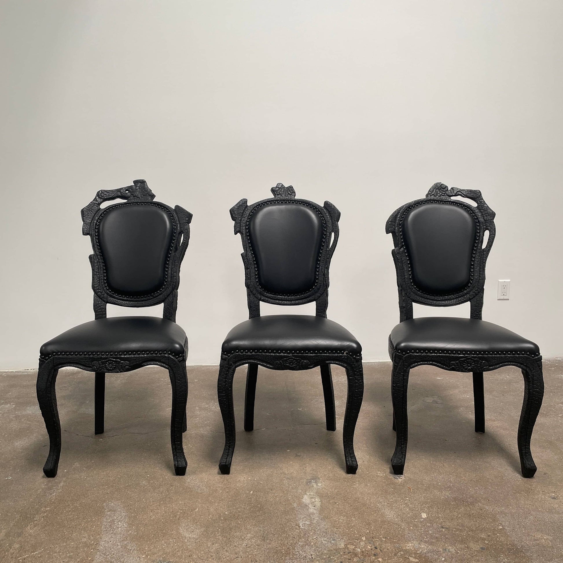 A set of seven Moooi Smoke Dining Side Chairs, crafted by Moooi in an ornate black finish with leather upholstery and cushioned seats and backs, arranged in two rows against a plain white background.